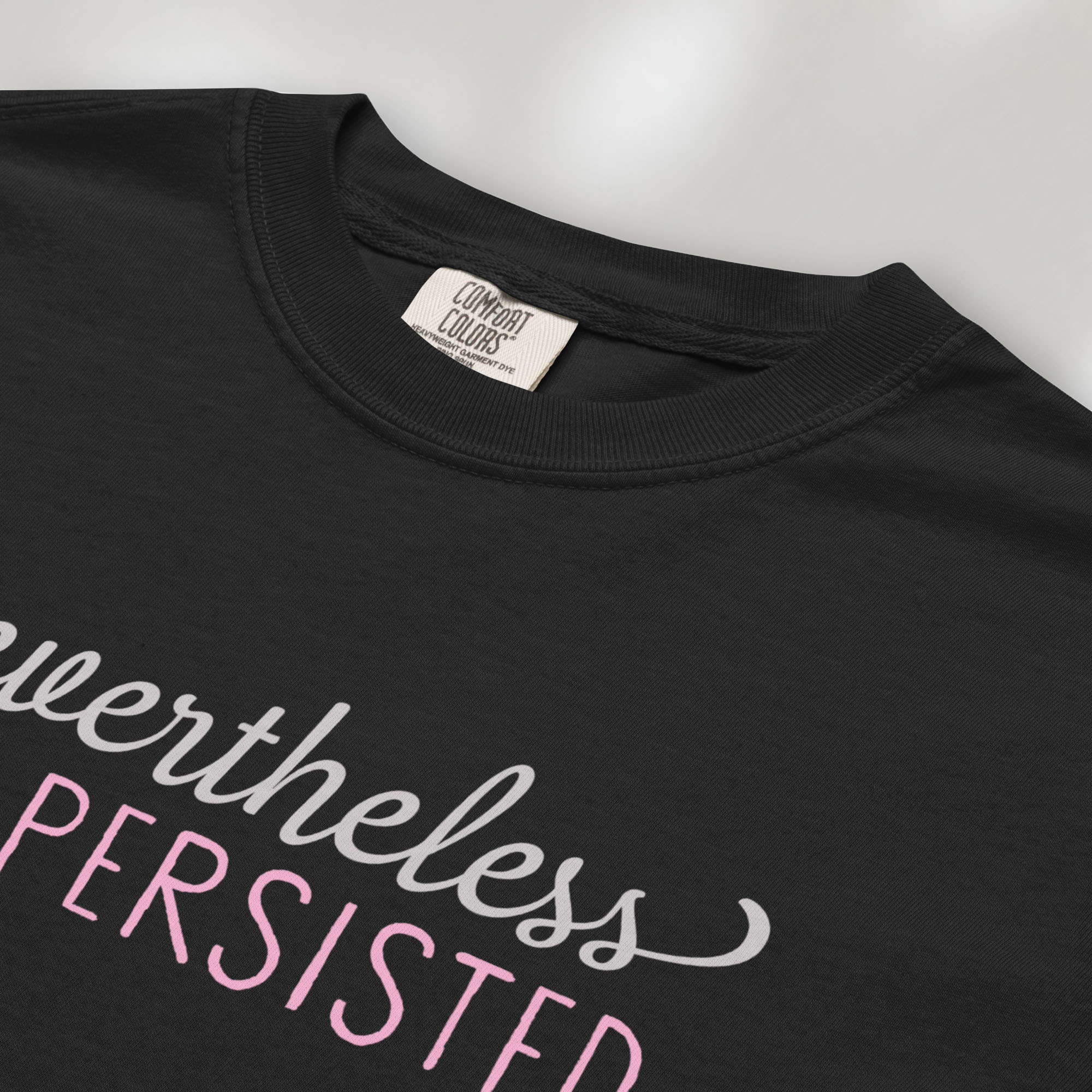 Closeup detail of black t-shirt with stylized text that reads "nevertheless she persisted."