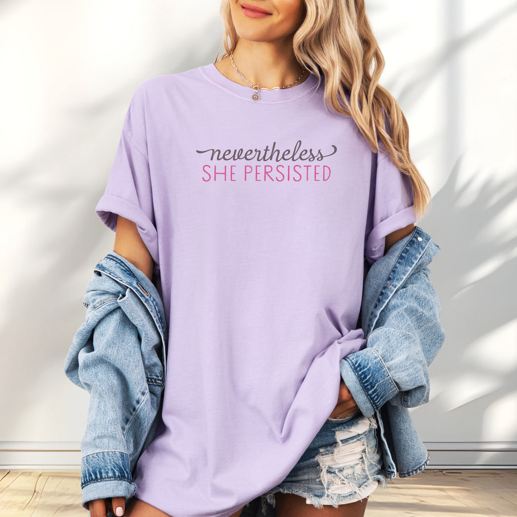 Female model wearing oversized orchid t-shirt with stylized text that reads "nevertheless she persisted."