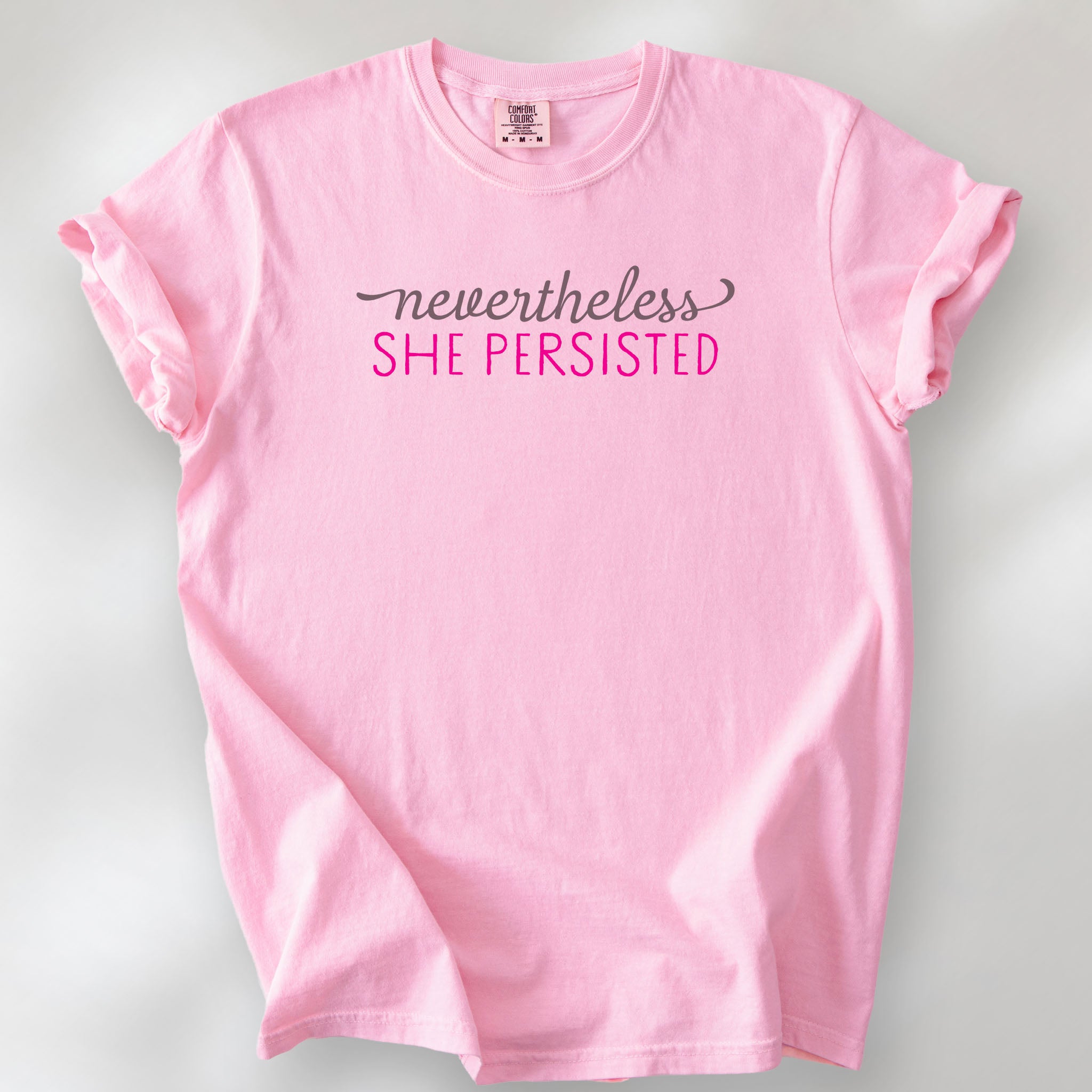 Blossom Comfort Colors garment-dyed tee with stylized text graphic that reads "nevertheless she persisted."