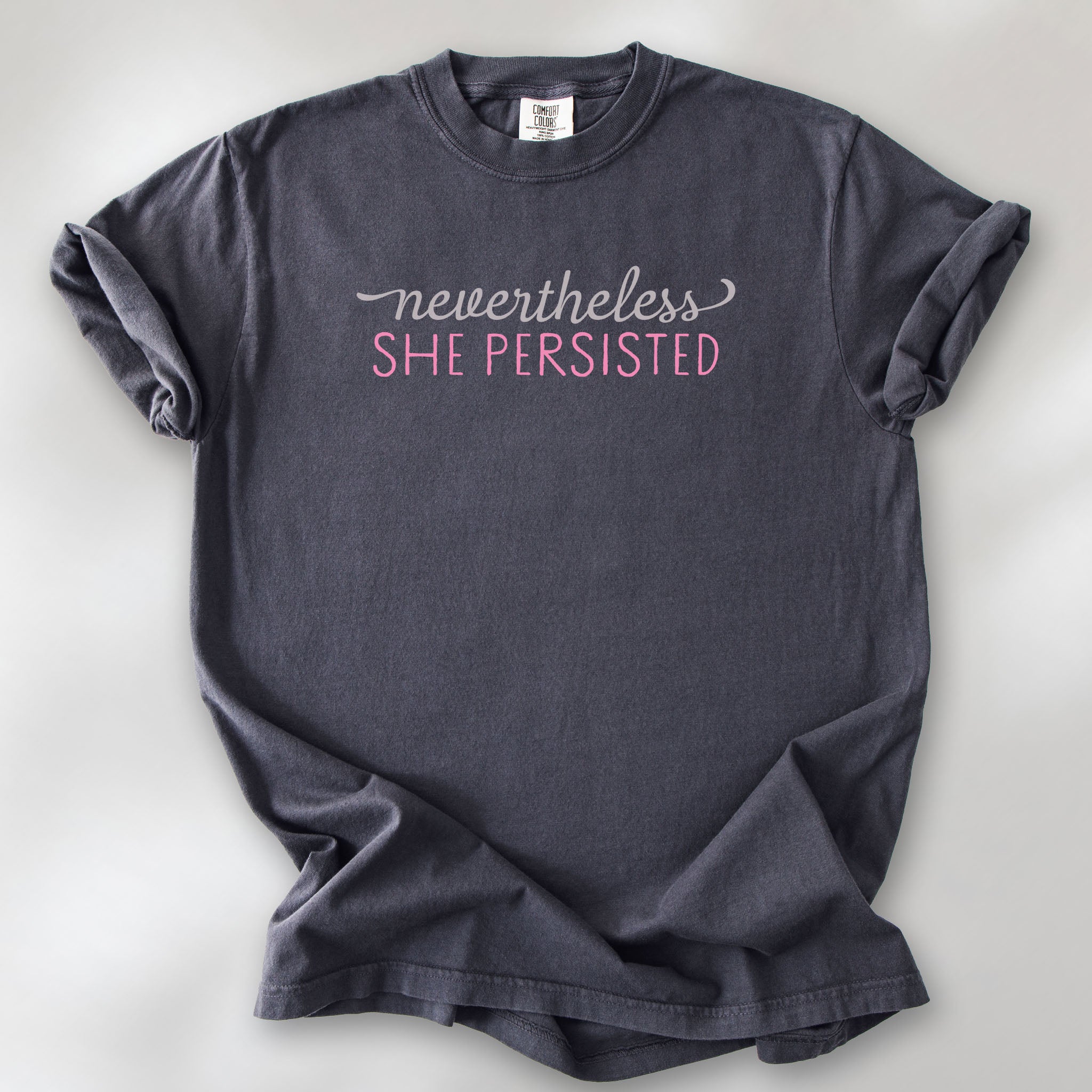 Graphite Comfort Colors garment-dyed tee with stylized text graphic that reads "nevertheless she persisted."