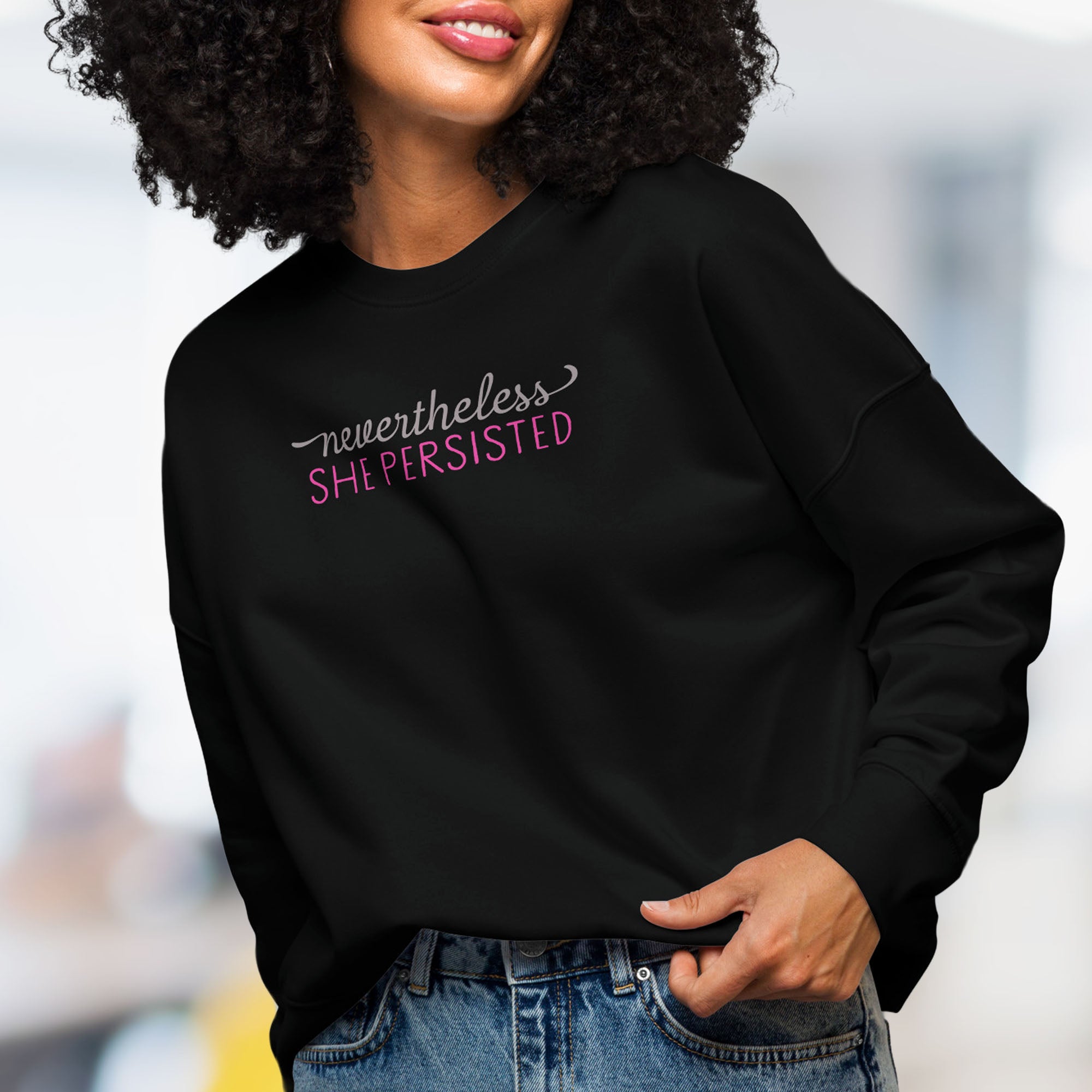 Front view of female model wearing black crewneck sweatshirt with stylized text graphic that reads 