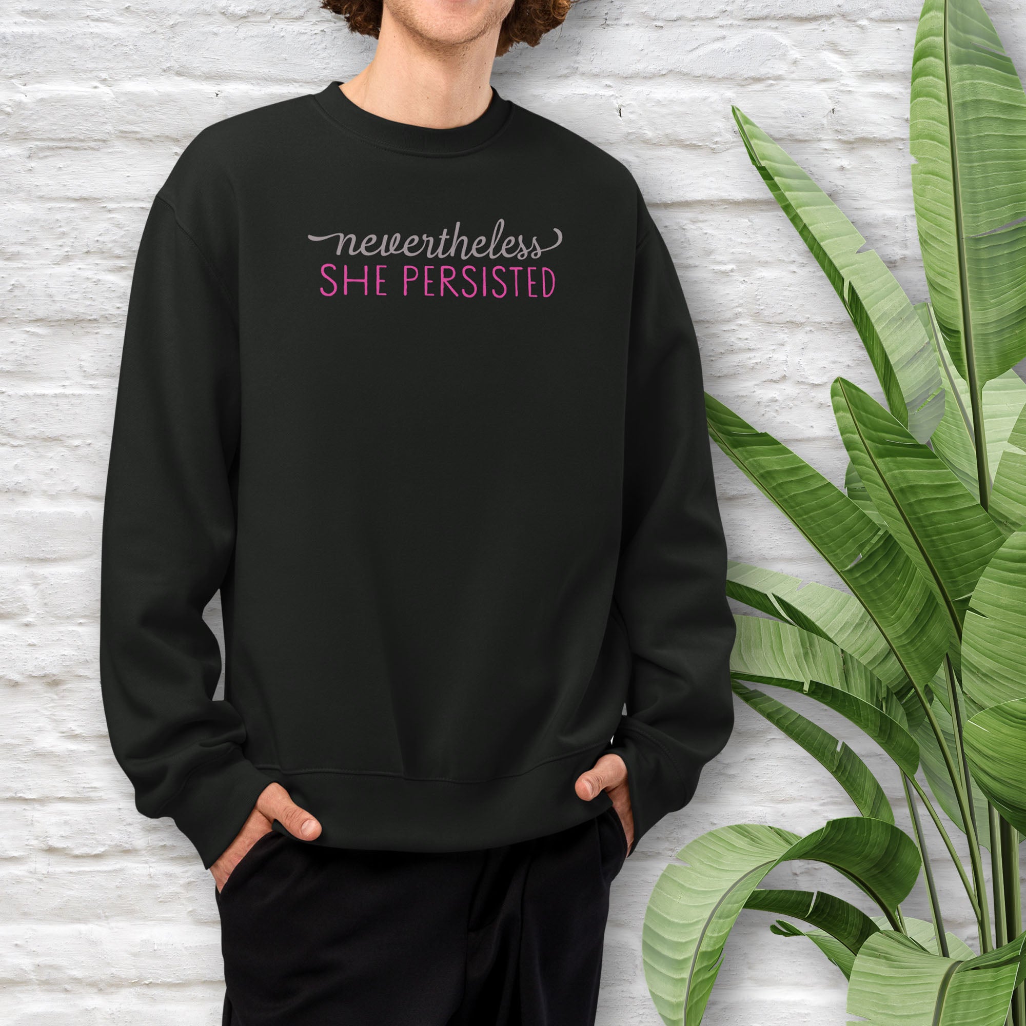 Male model wearing black sweatshirt with styled text that reads "nevertheless, she persisted".