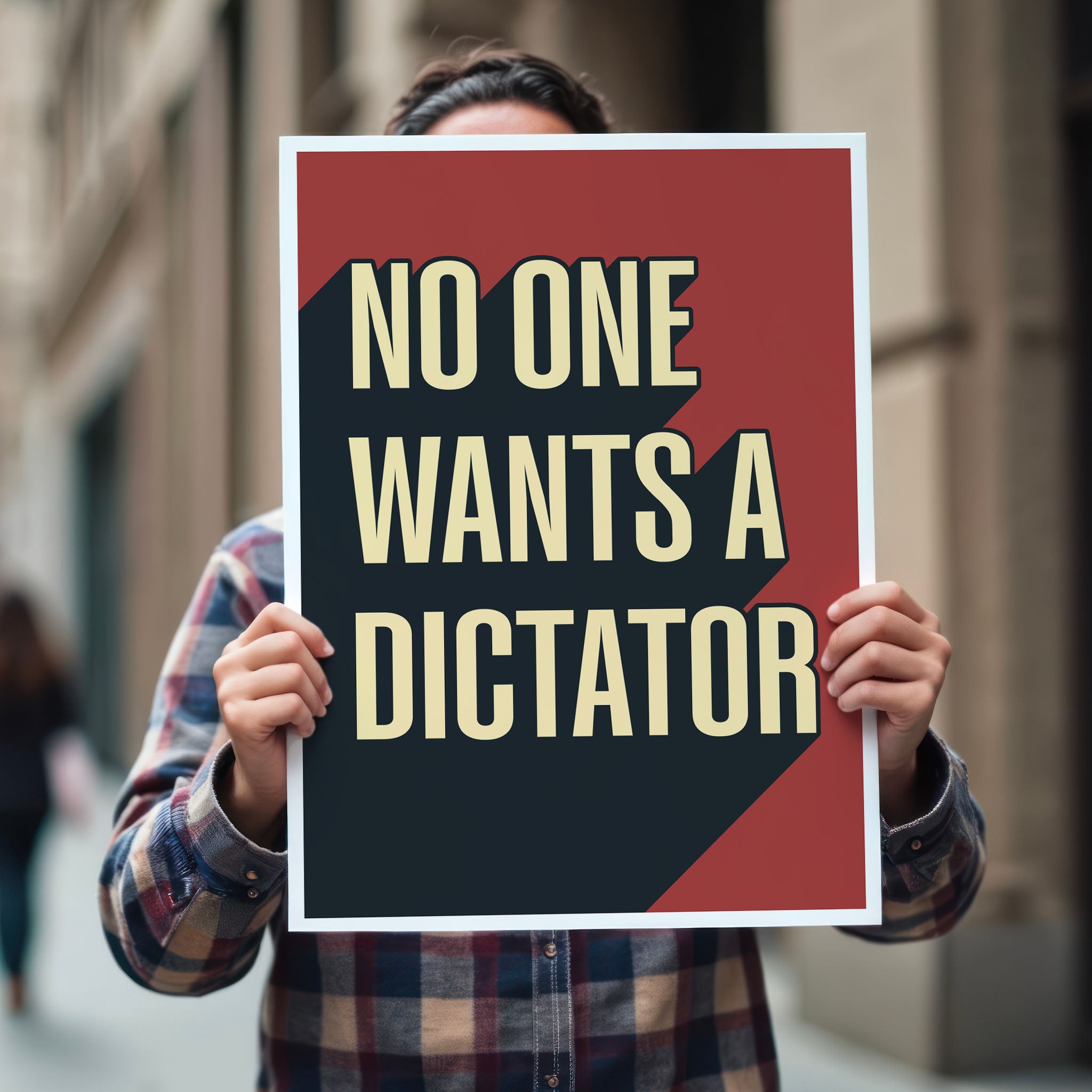 Person holding anti-Trump protest sign with bold text reading “No One Wants a Dictator” in cream letters on red background with black shadow.