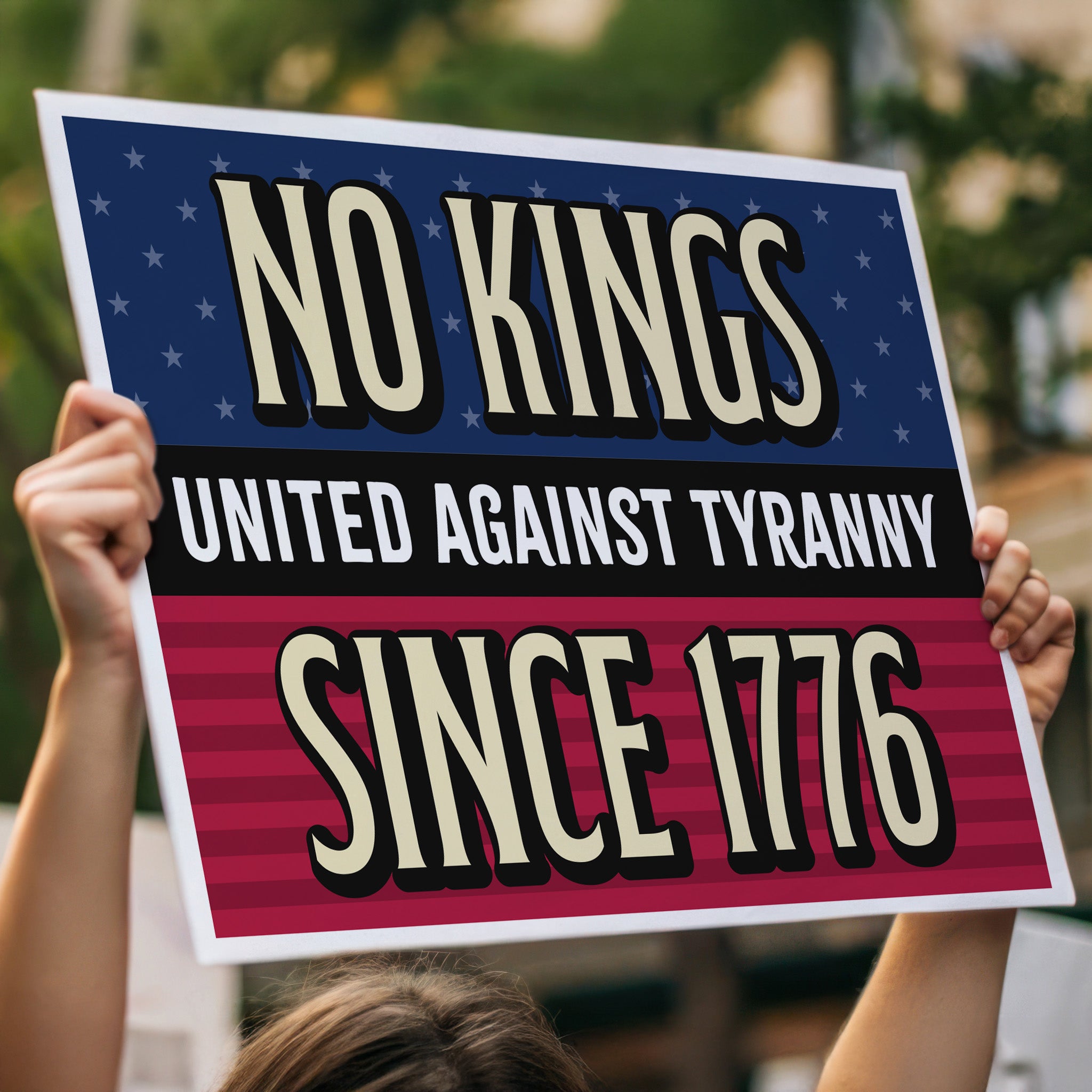 Person in a crowd holding protest sign with blue and red stars and stripes background and gold and white text reading "No Kings – United Against Tyranny – Since 1776" – a defiant, anti-Trump message rejecting authoritarianism and honoring America's revolutionary roots.