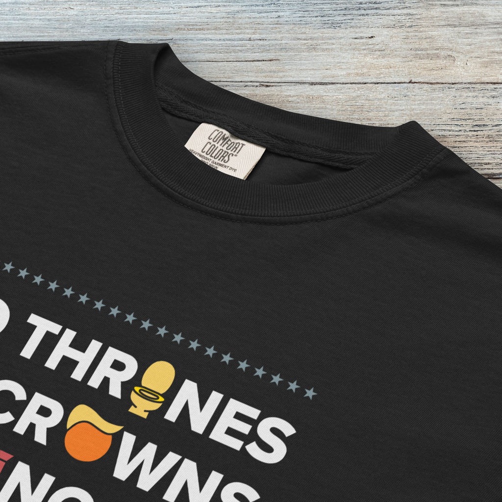 Closeup detail of black t-shirt with bold text reading “No Thrones No Crowns No Kings” featuring satirical Trump graphics: gold toilet, yellow hair, and long red tie, original anti-Trump protest shirt.