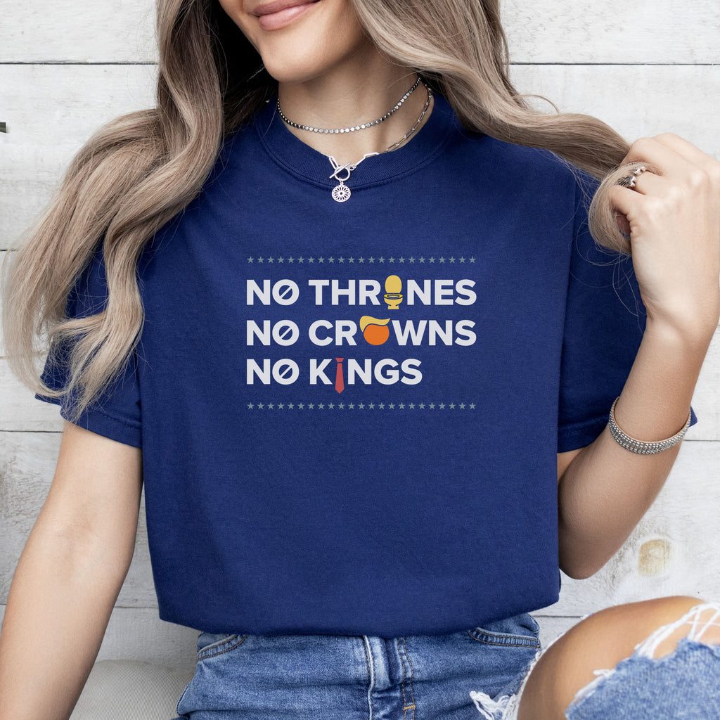 Female model wearing true navy t-shirt with bold text reading “No Thrones No Crowns No Kings” featuring satirical Trump graphics: gold toilet, yellow hair, and long red tie, original anti-Trump protest shirt.