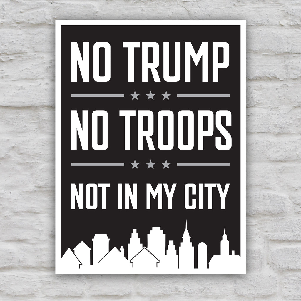 Black and white version of protest sign with bold white text reading “No Trump No Troops Not in My City” over a dark background with a city skyline silhouette.