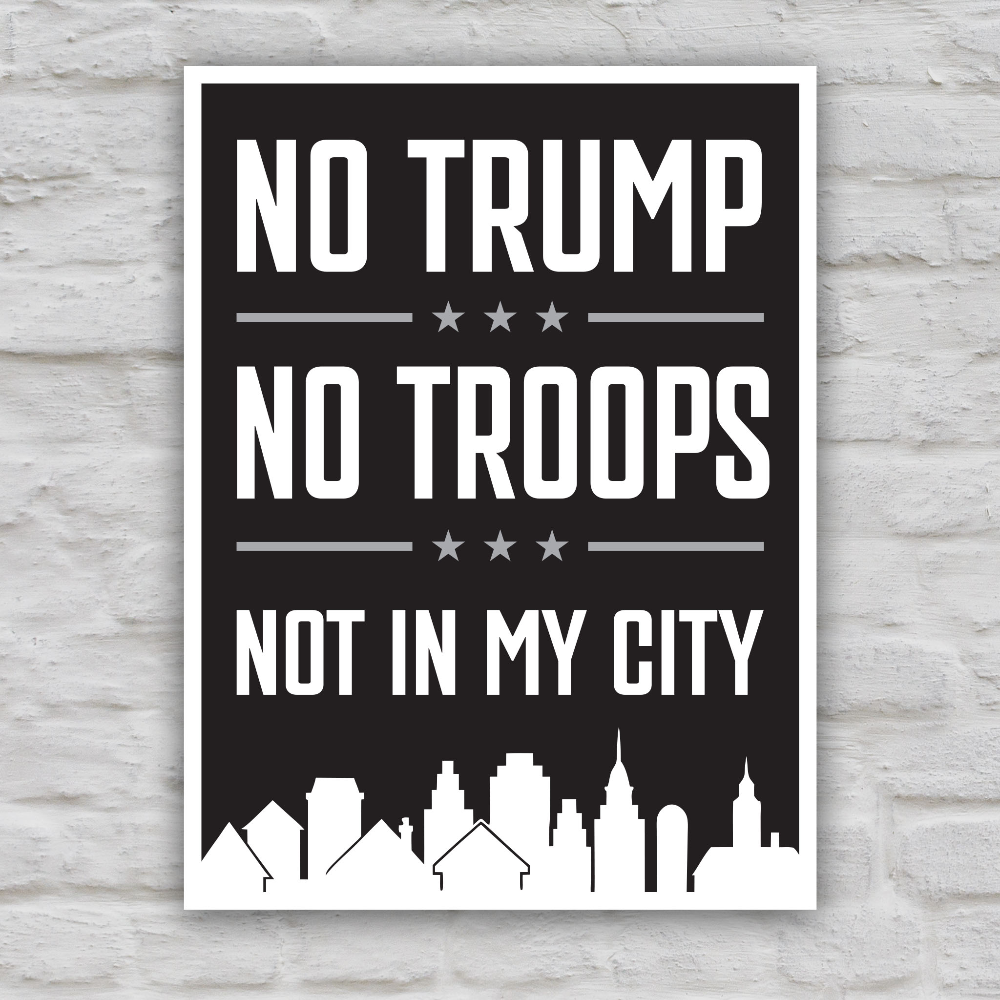 Black and white version of protest sign with bold white text reading “No Trump No Troops Not in My City” over a dark background with a city skyline silhouette.
