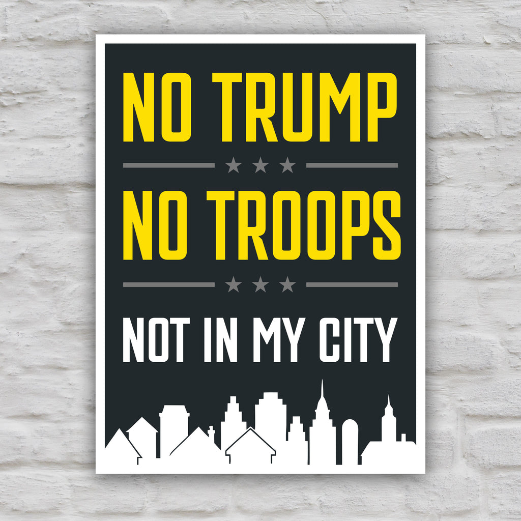 Color version of protest sign with bold yellow and white text reading “No Trump No Troops Not in My City” over a dark background with a city skyline silhouette.