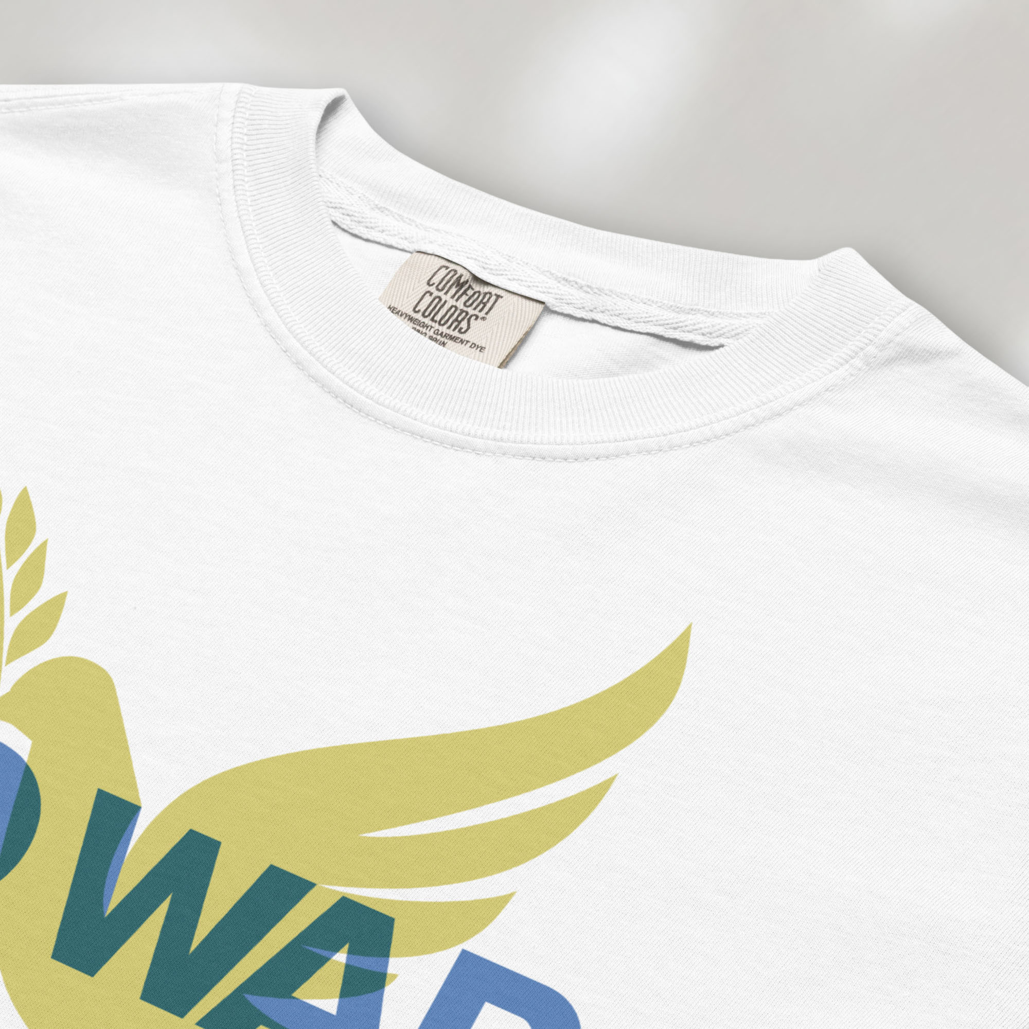 CLoseup detail of white t-shirt featuring blue “No War” text over a yellow peace dove carrying an olive branch that forks into a peace sign over the text..