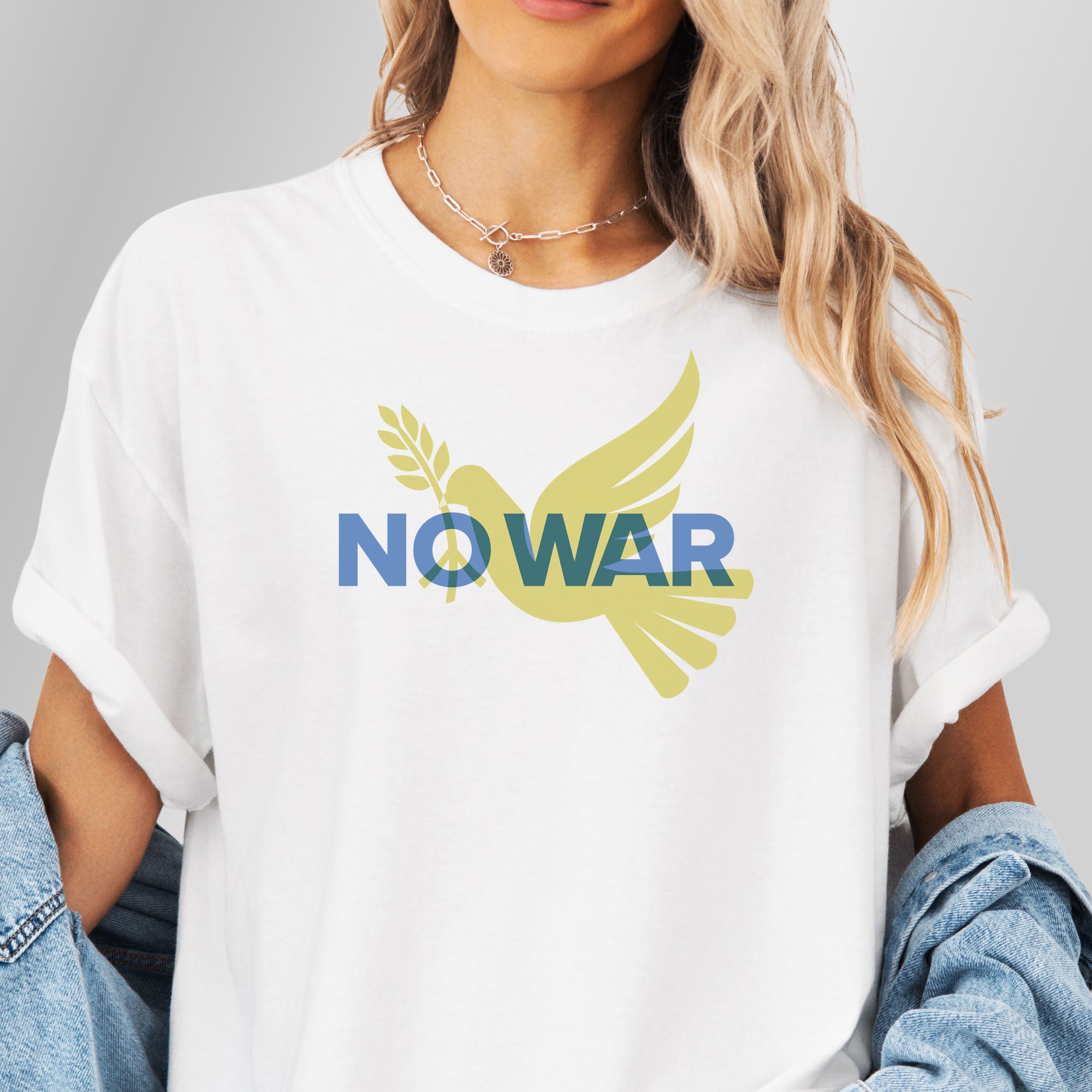 Female model wearing oversized white t-shirt featuring blue “No War” text over a yellow peace dove carrying an olive branch that forks into a peace sign over the text..