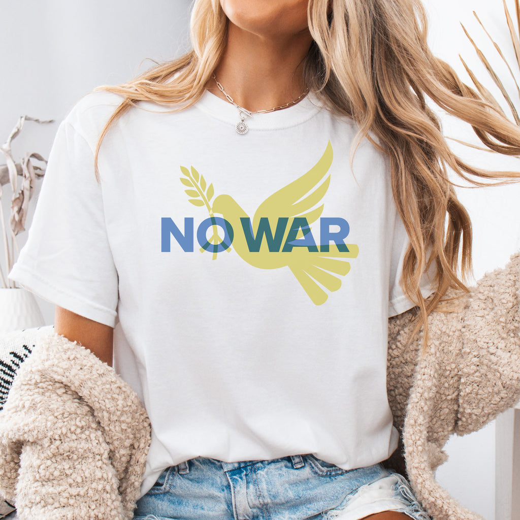 Female model wearing white t-shirt featuring blue “No War” text over a yellow peace dove carrying an olive branch that forks into a peace sign over the text..