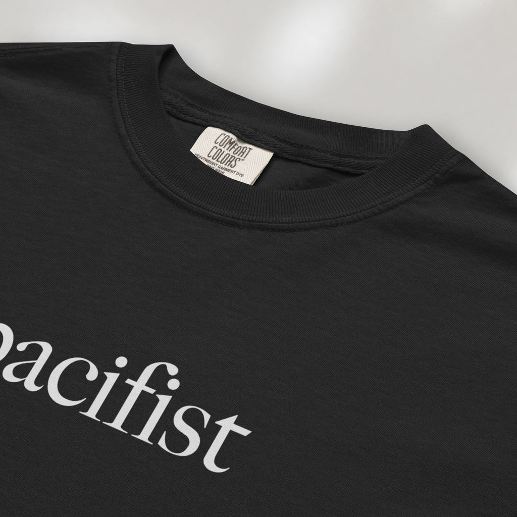 Closeup detail of black t-shirt with minimalist serif text reading "pacifist."