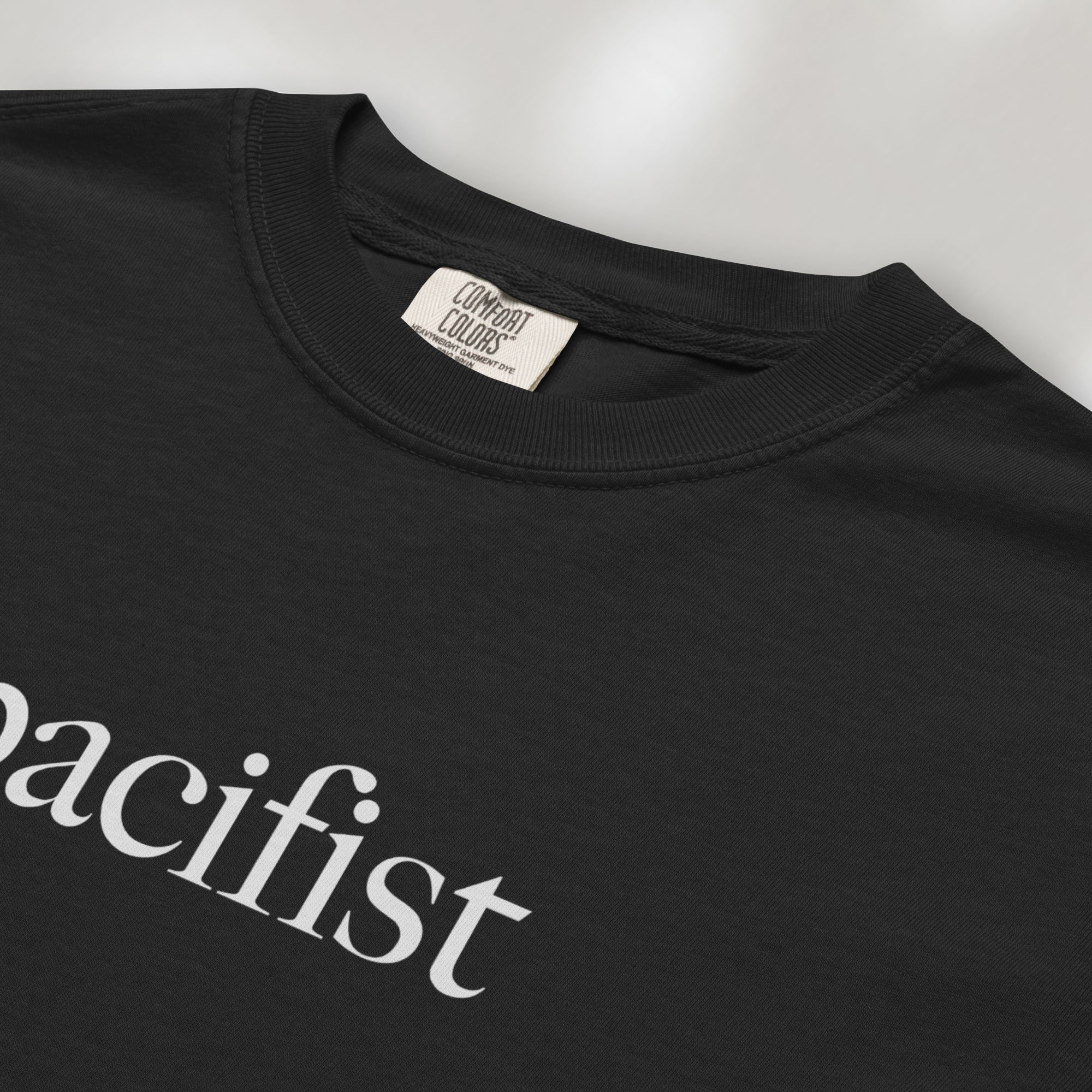 Closeup detail of black t-shirt with minimalist serif text reading "pacifist."