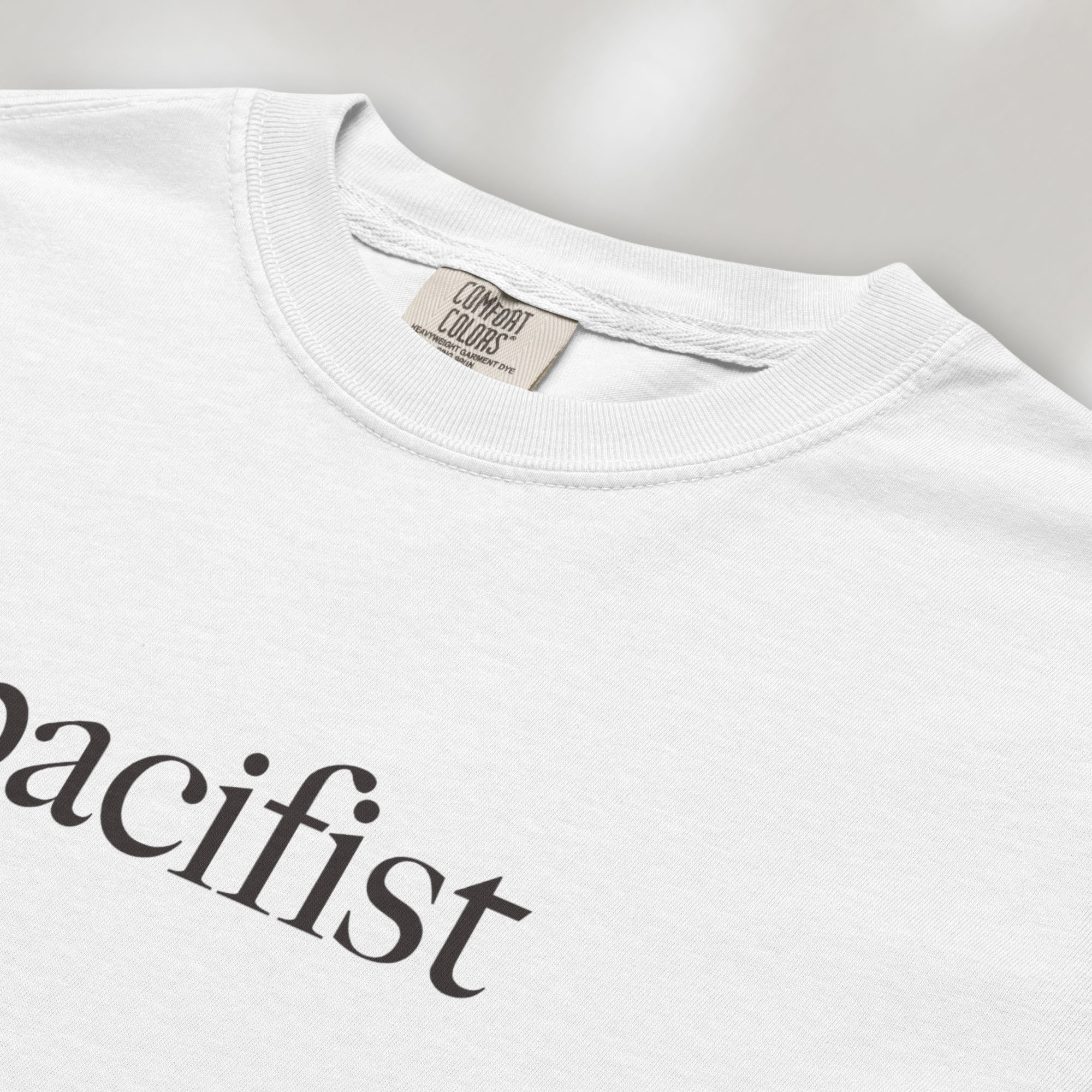 Closeup detail of white t-shirt with minimalist serif text reading "pacifist."