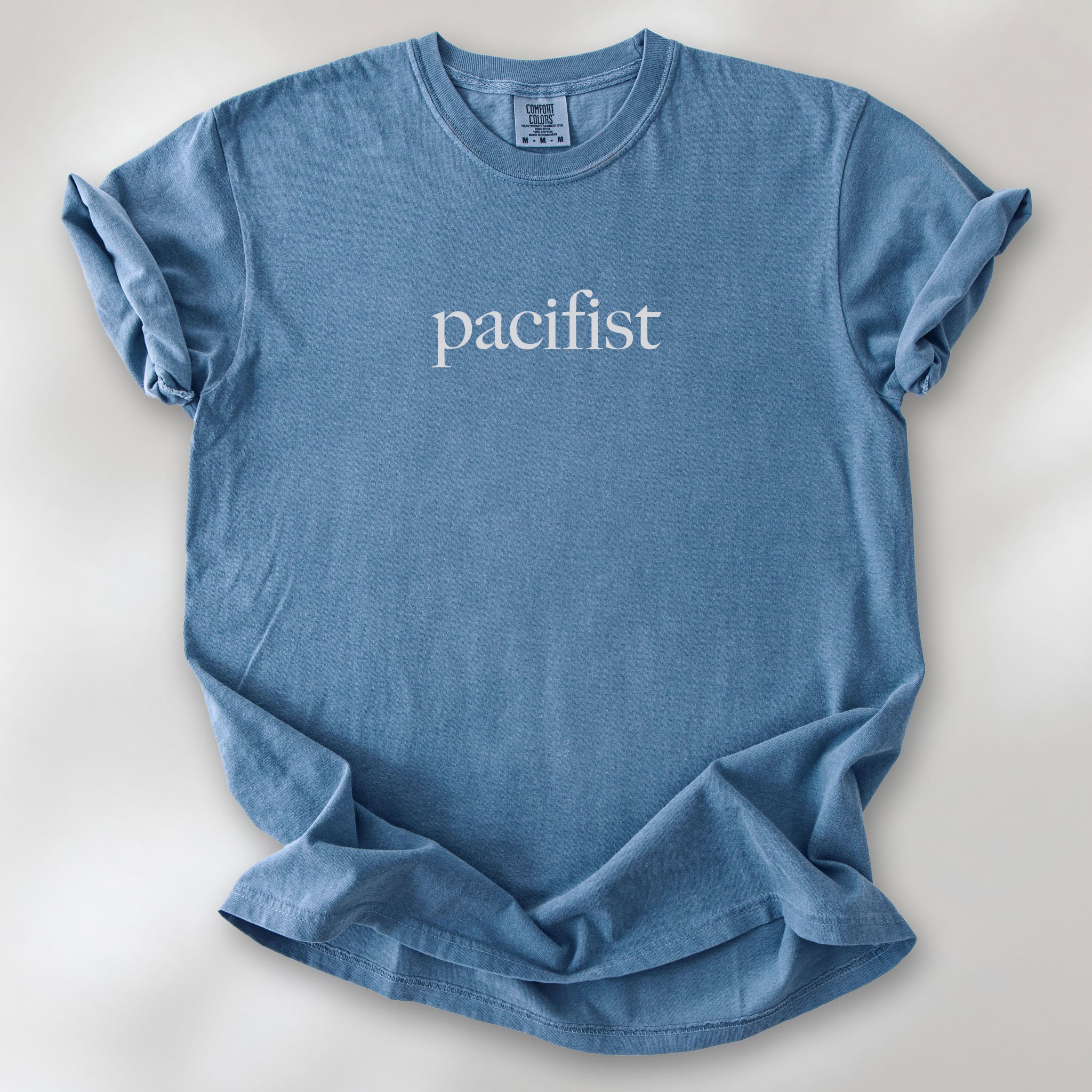Blue jean t-shirt with minimalist serif text reading "pacifist."