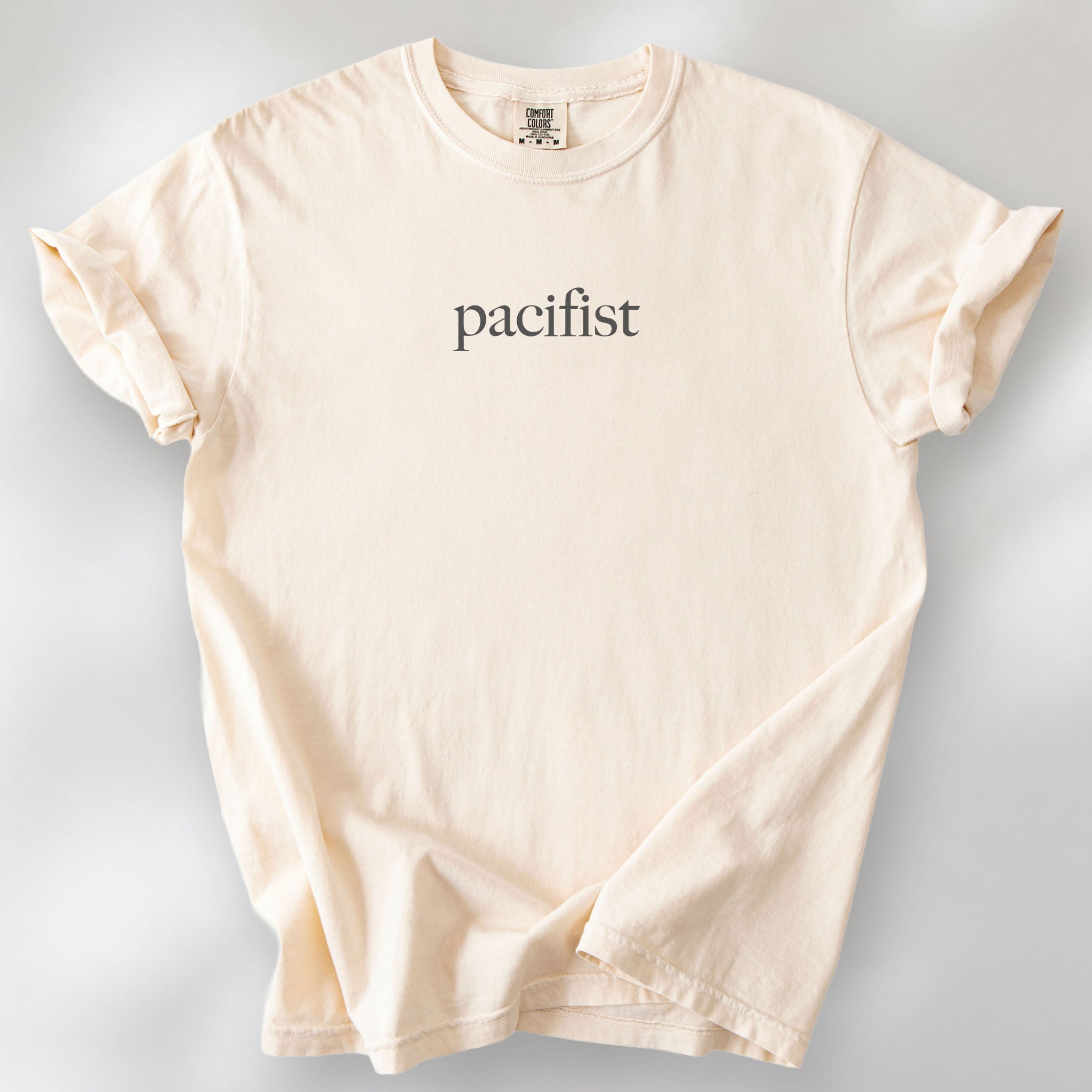 Ivory t-shirt with minimalist serif text reading "pacifist."