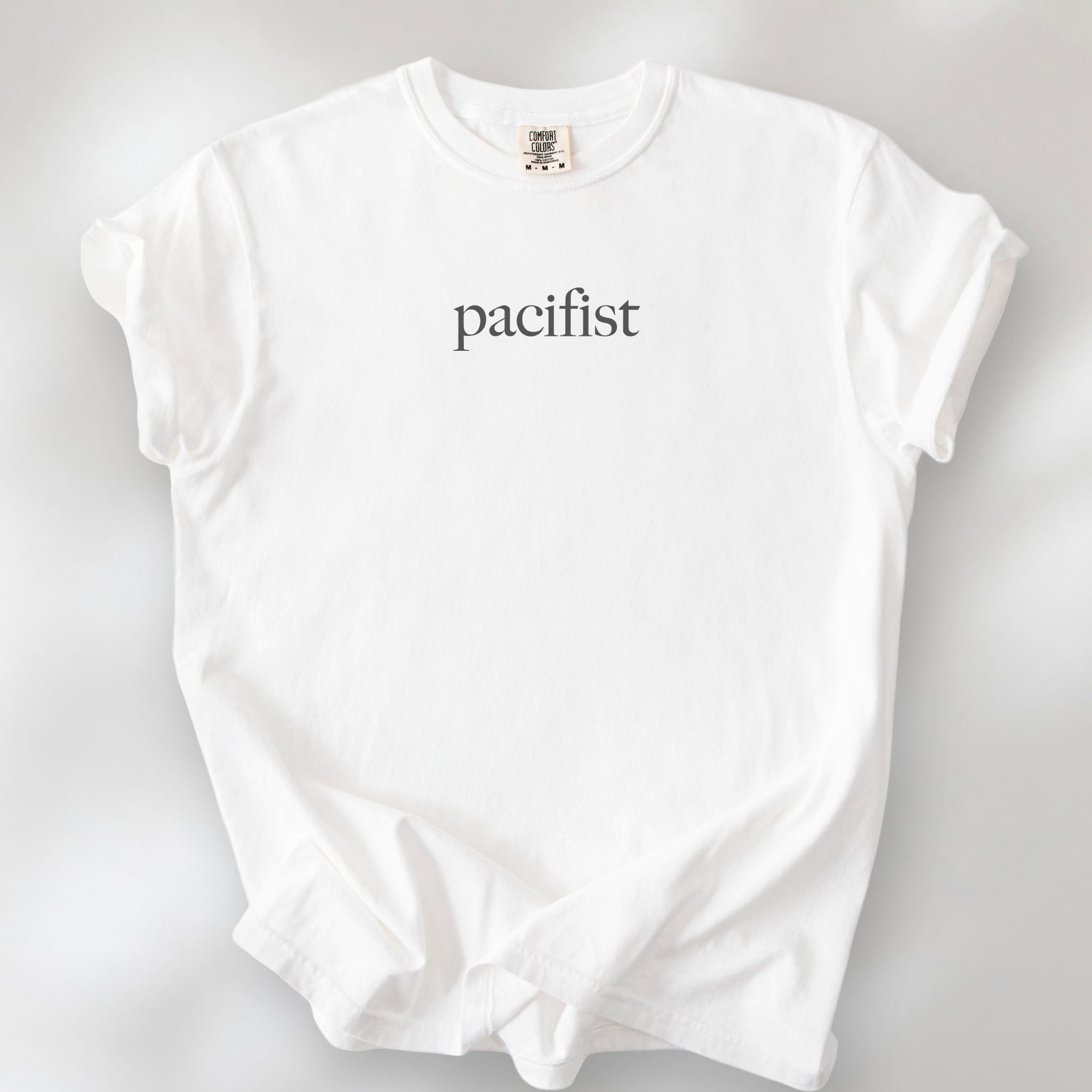 White t-shirt with minimalist serif text reading "pacifist."