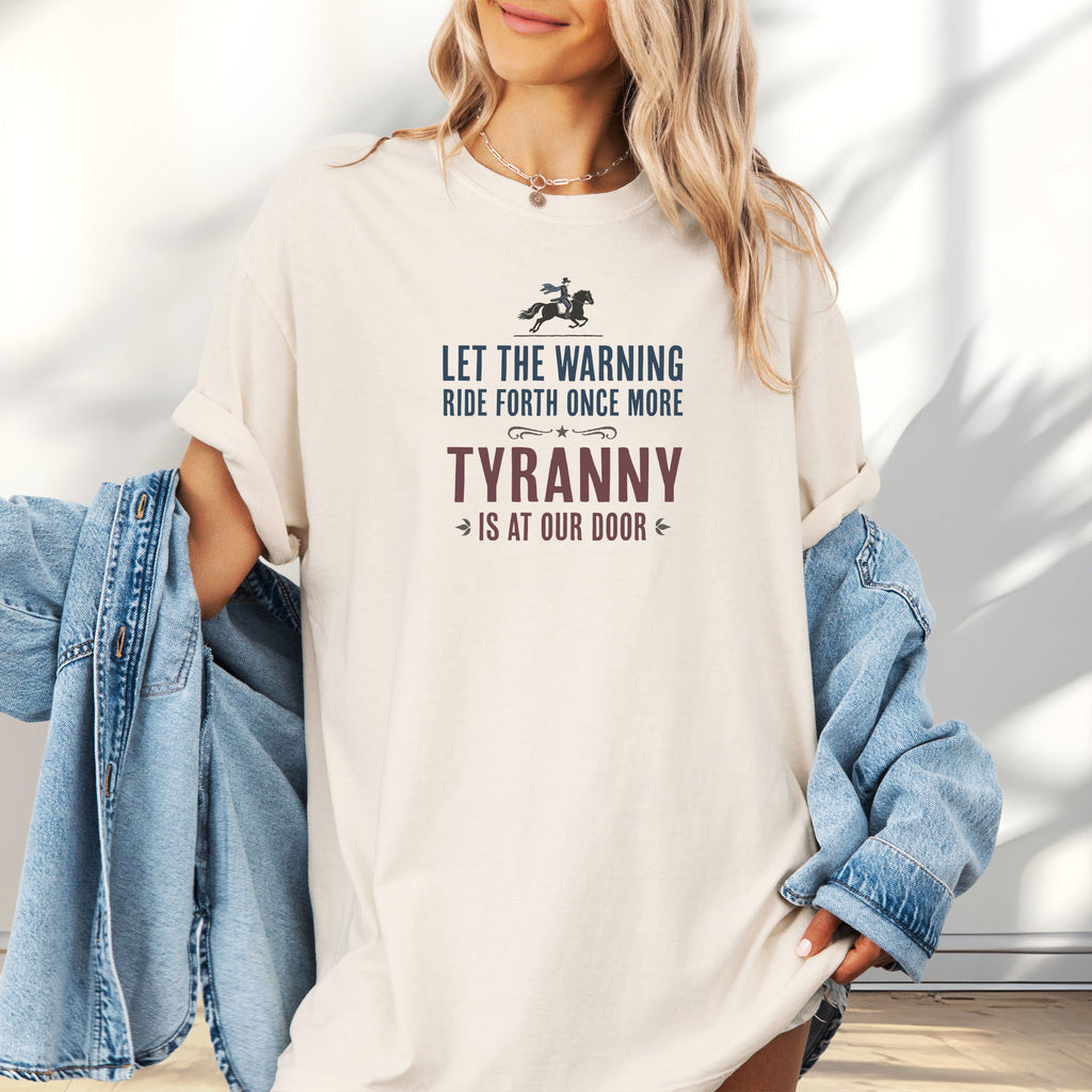Female model wearing oversized ivory t-shirt with a silhouette of Paul Revere on horseback and the text “Let the warning ride forth once more – Tyranny is at our door” in blue and red.