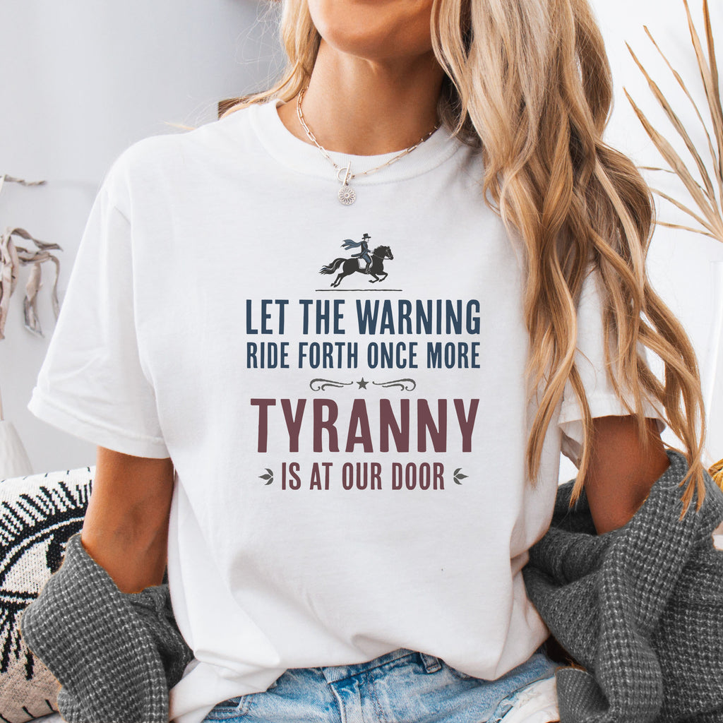 Female model wearing white t-shirt with a silhouette of Paul Revere on horseback and the text “Let the warning ride forth once more – Tyranny is at our door” in blue and red.