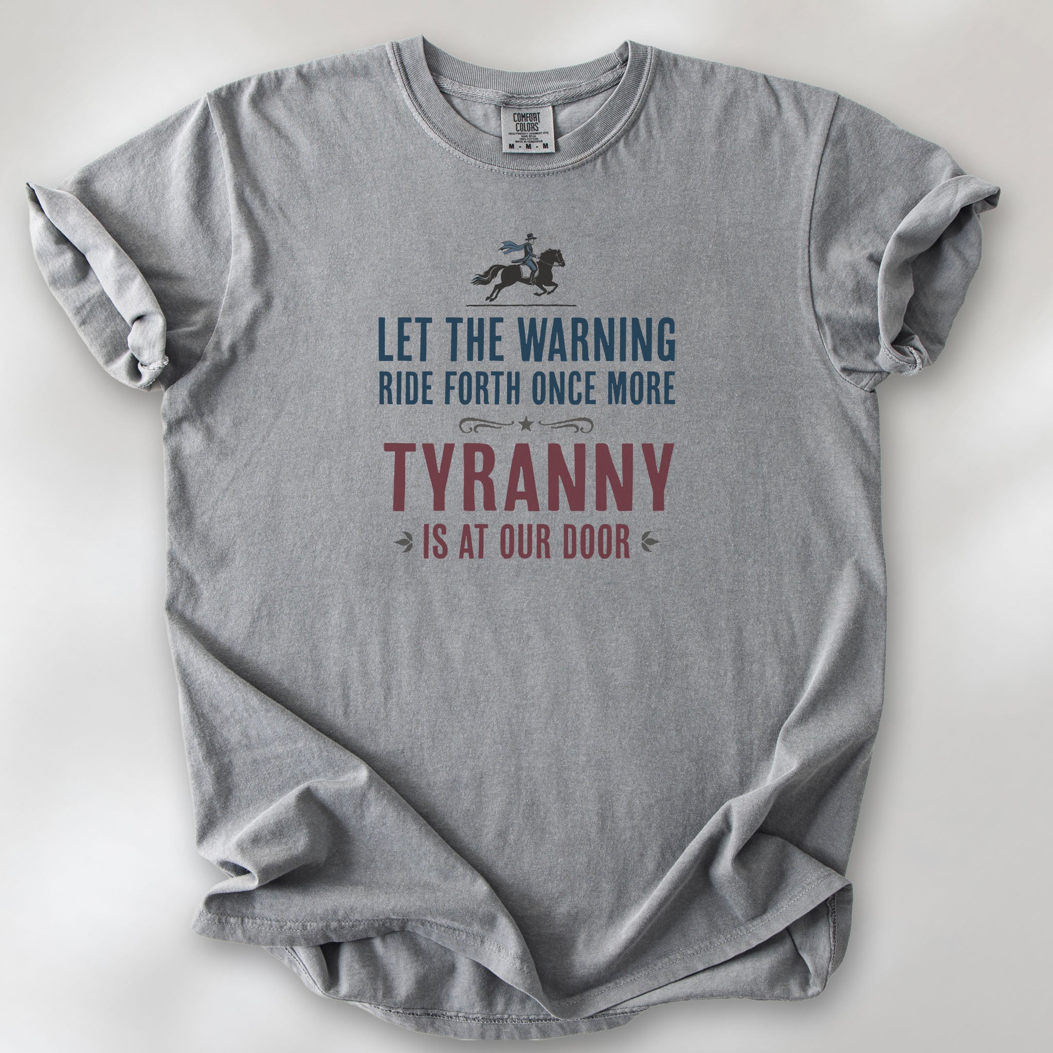 Grey t-shirt with a silhouette of Paul Revere on horseback and the text “Let the warning ride forth once more – Tyranny is at our door” in blue and red.