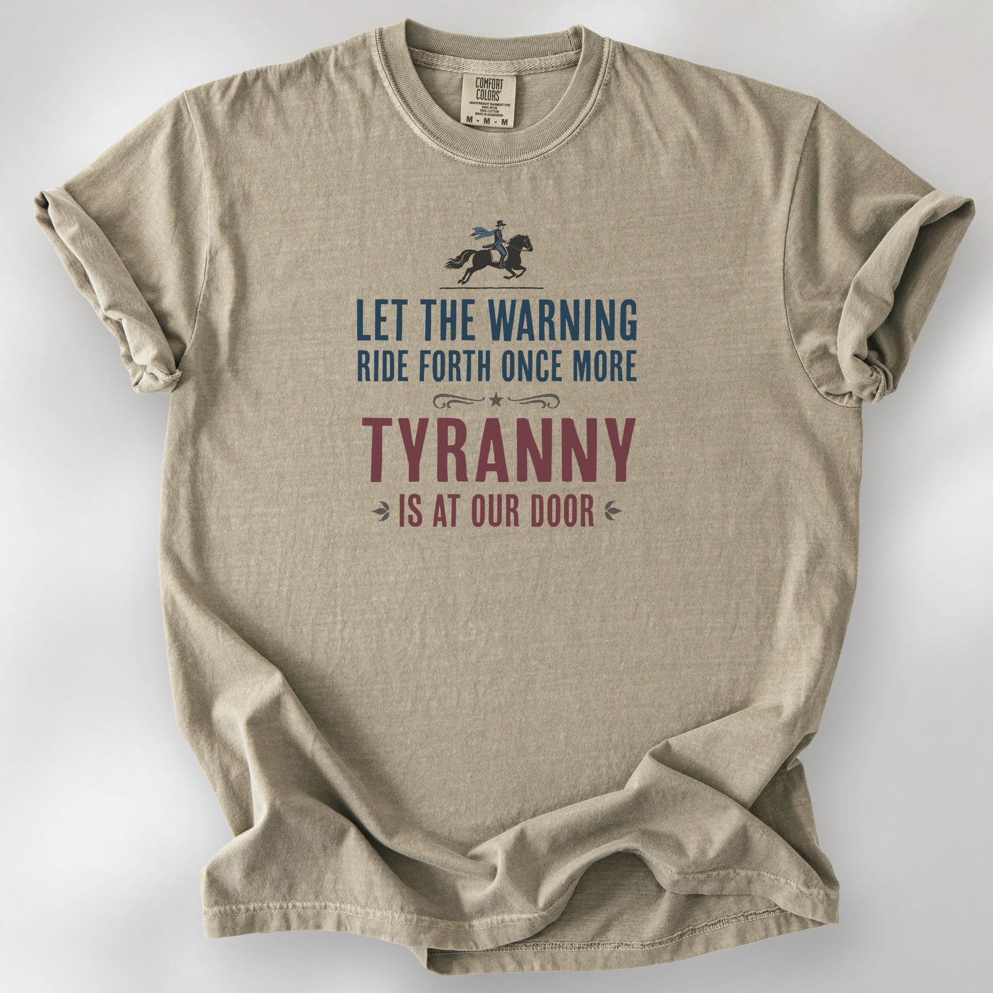 Khaki t-shirt with a silhouette of Paul Revere on horseback and the text “Let the warning ride forth once more – Tyranny is at our door” in blue and red.