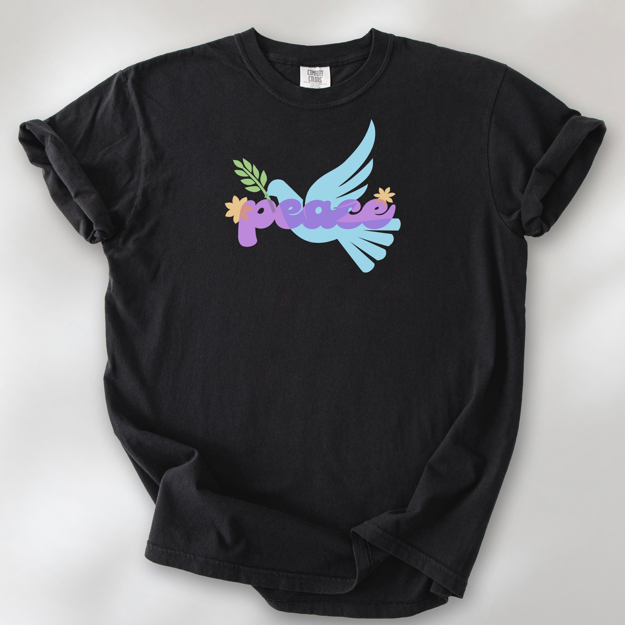 Black t-shirt featuring a colorful retro peace dove carrying an olive branch with the word "peace" in groovy 1970s-style lettering. 