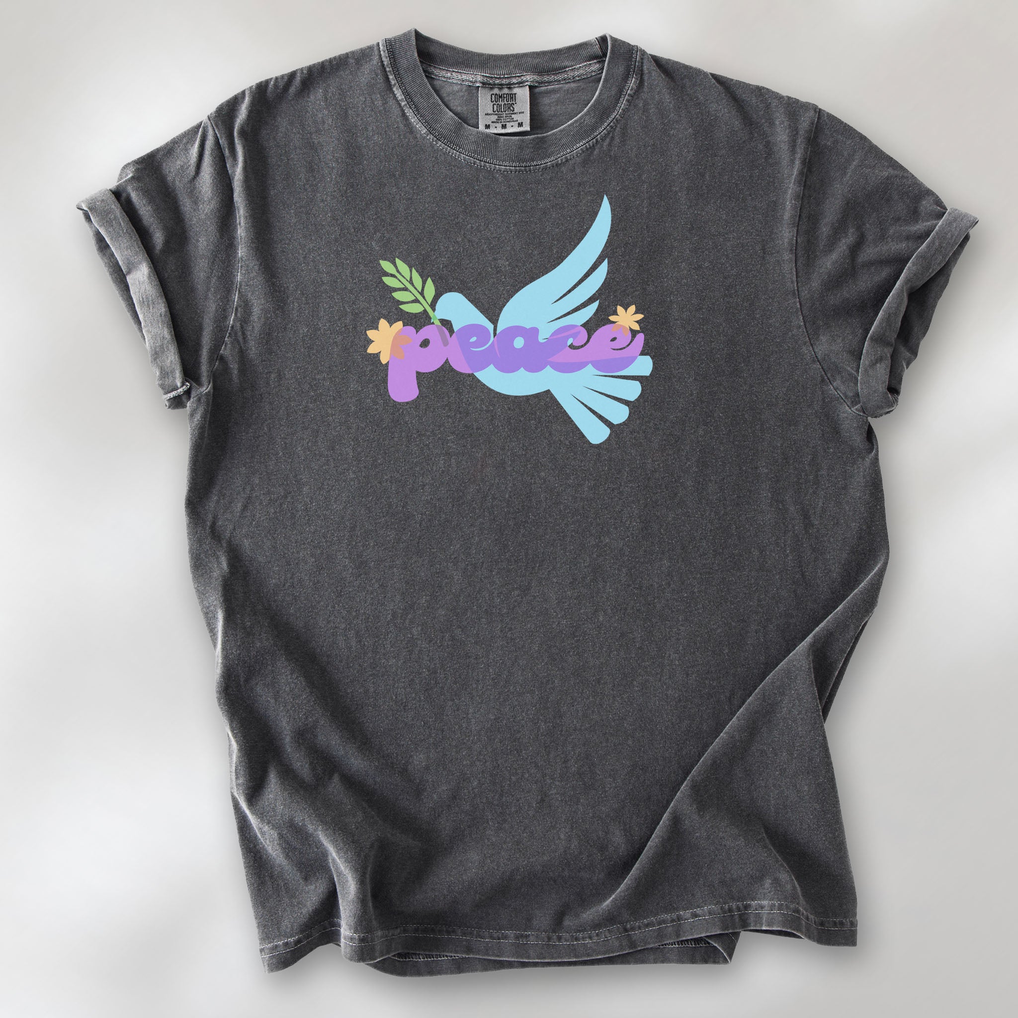 Pepper t-shirt featuring a colorful retro peace dove carrying an olive branch with the word "peace" in groovy 1970s-style lettering. 