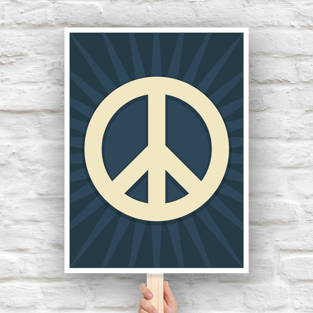 Protest sign with a large pale gold peace symbol in the center on a dark blue background with a burst emanating from the symbol.