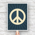 Protest sign with a large pale gold peace symbol in the center on a dark blue background with a burst emanating from the symbol.