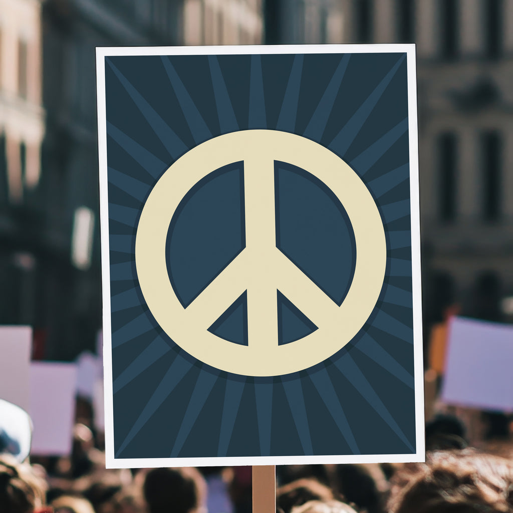 Protest sign held high in a crowd with a large pale gold peace symbol in the center on a dark blue background with a burst emanating from the symbol.