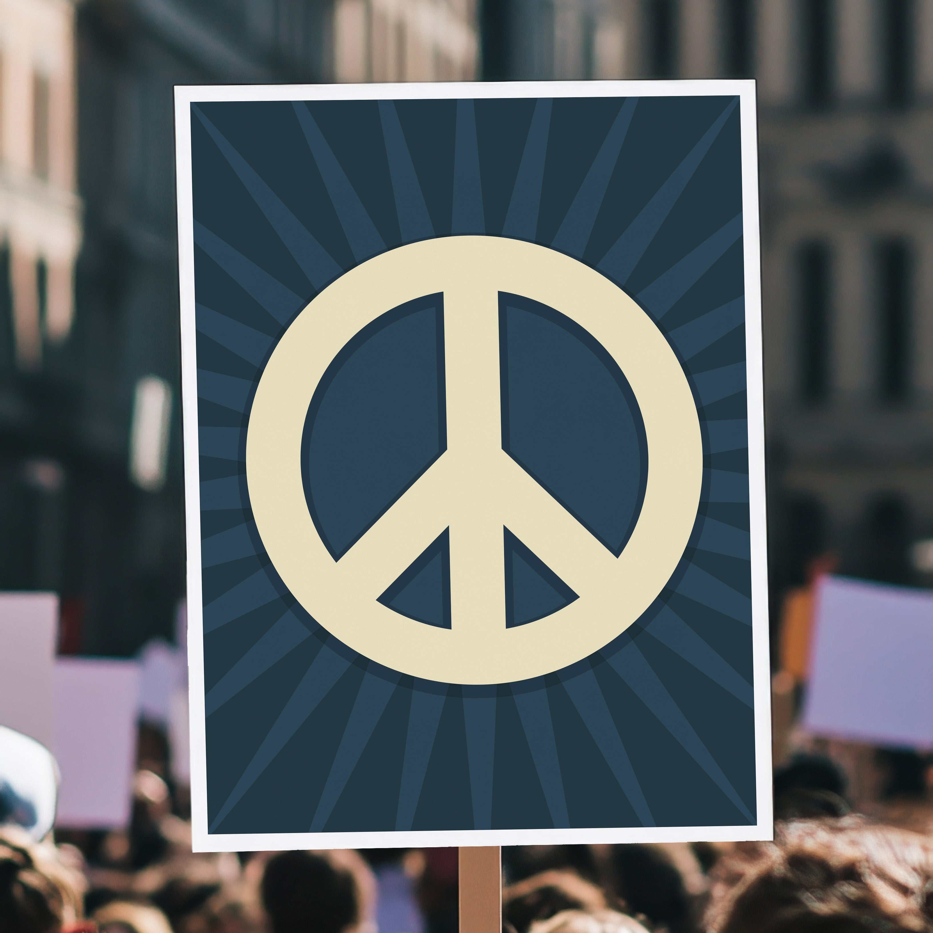 Protest sign held high in a crowd with a large pale gold peace symbol in the center on a dark blue background with a burst emanating from the symbol.