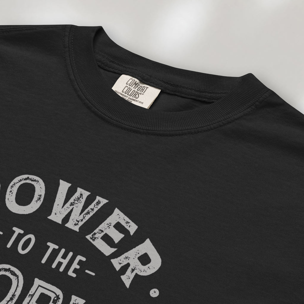 Closeup detail of black t-shirt with vintage-style distressed text reading “Power to the People — Show Up Speak Out”.