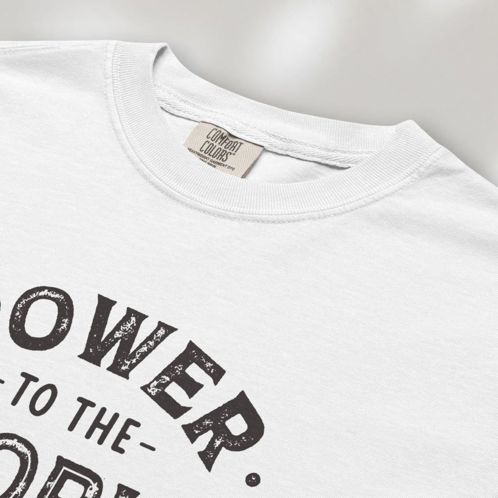 CLoseup detail of white t-shirt with vintage-style distressed text reading “Power to the People — Show Up Speak Out”.