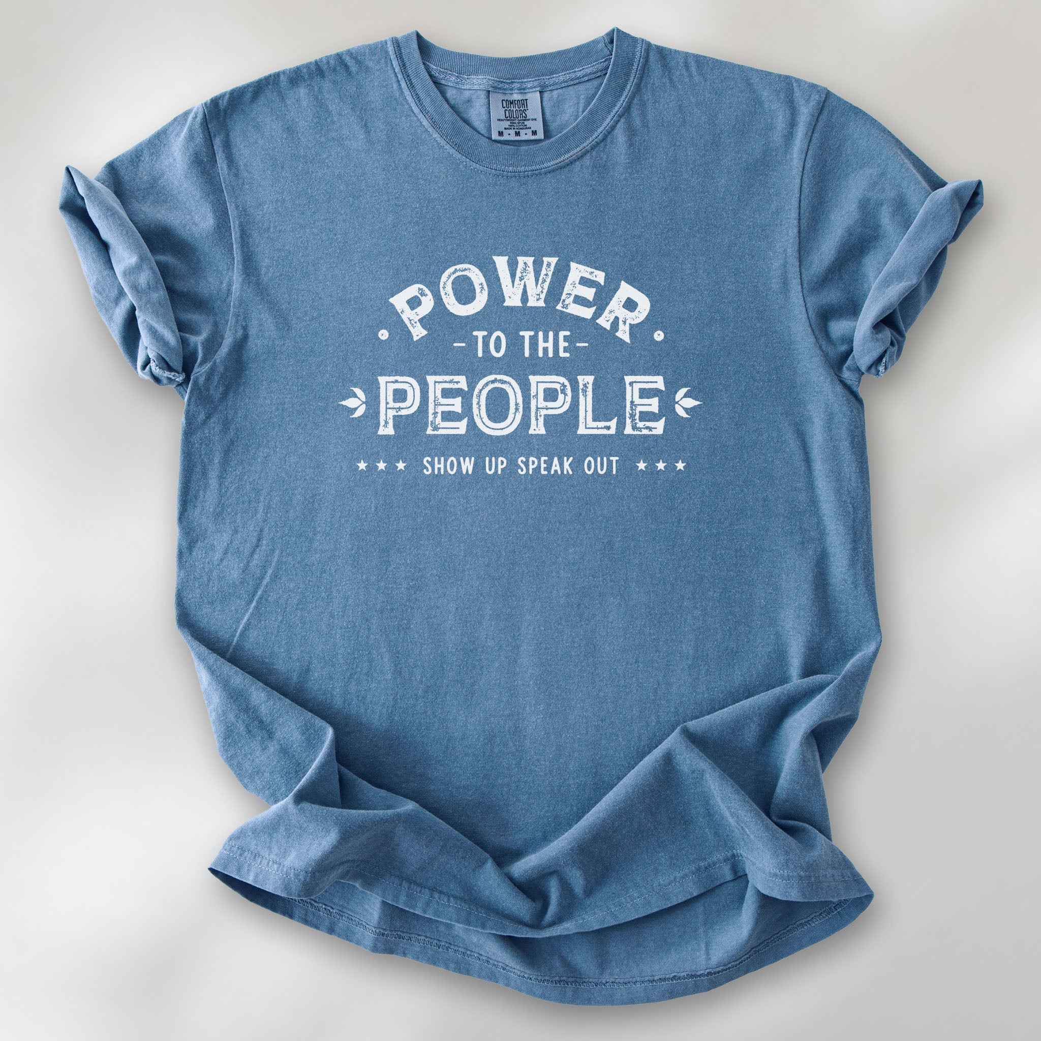 Blue jean t-shirt with vintage-style distressed text reading “Power to the People — Show Up Speak Out”.