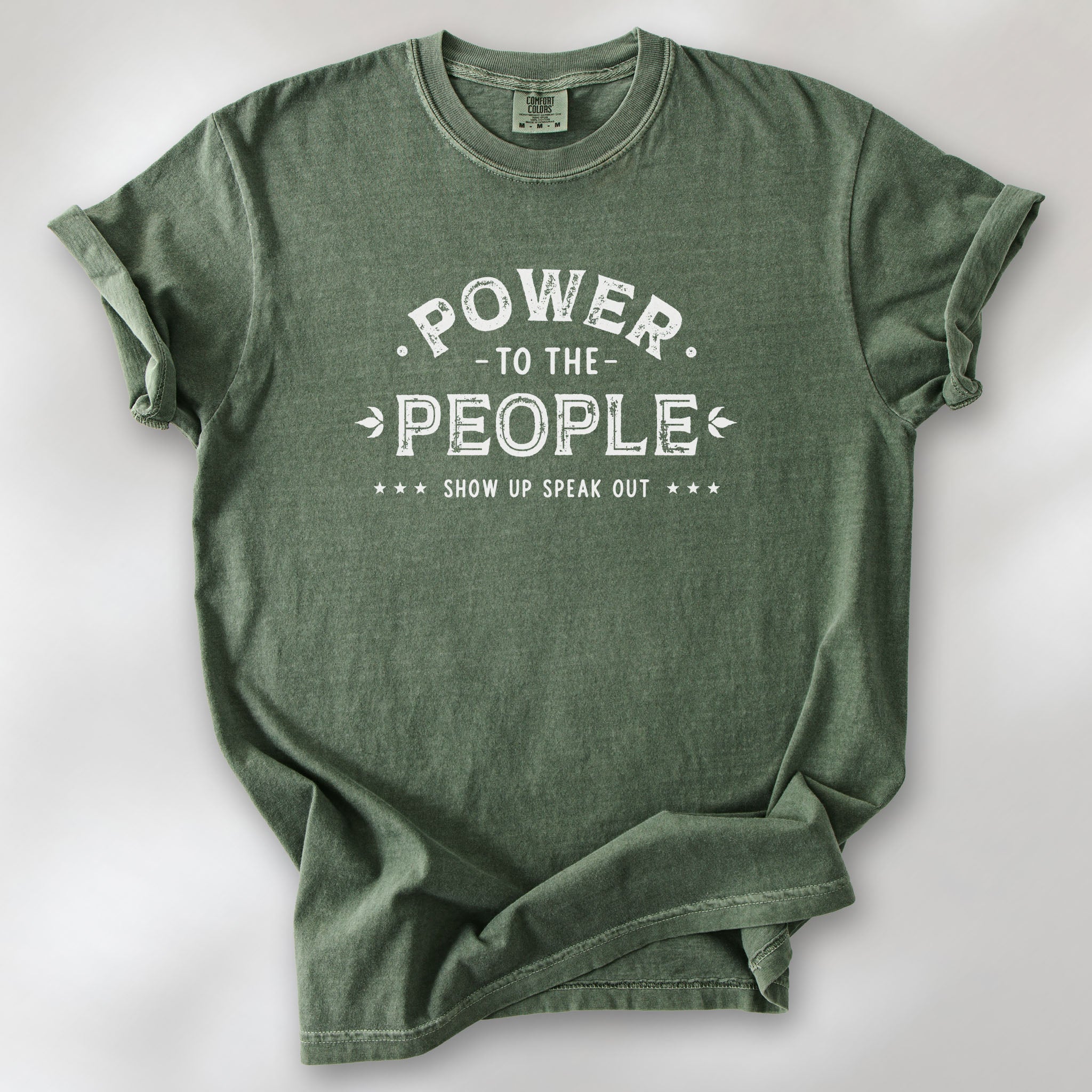 Moss t-shirt with vintage-style distressed text reading “Power to the People — Show Up Speak Out”.