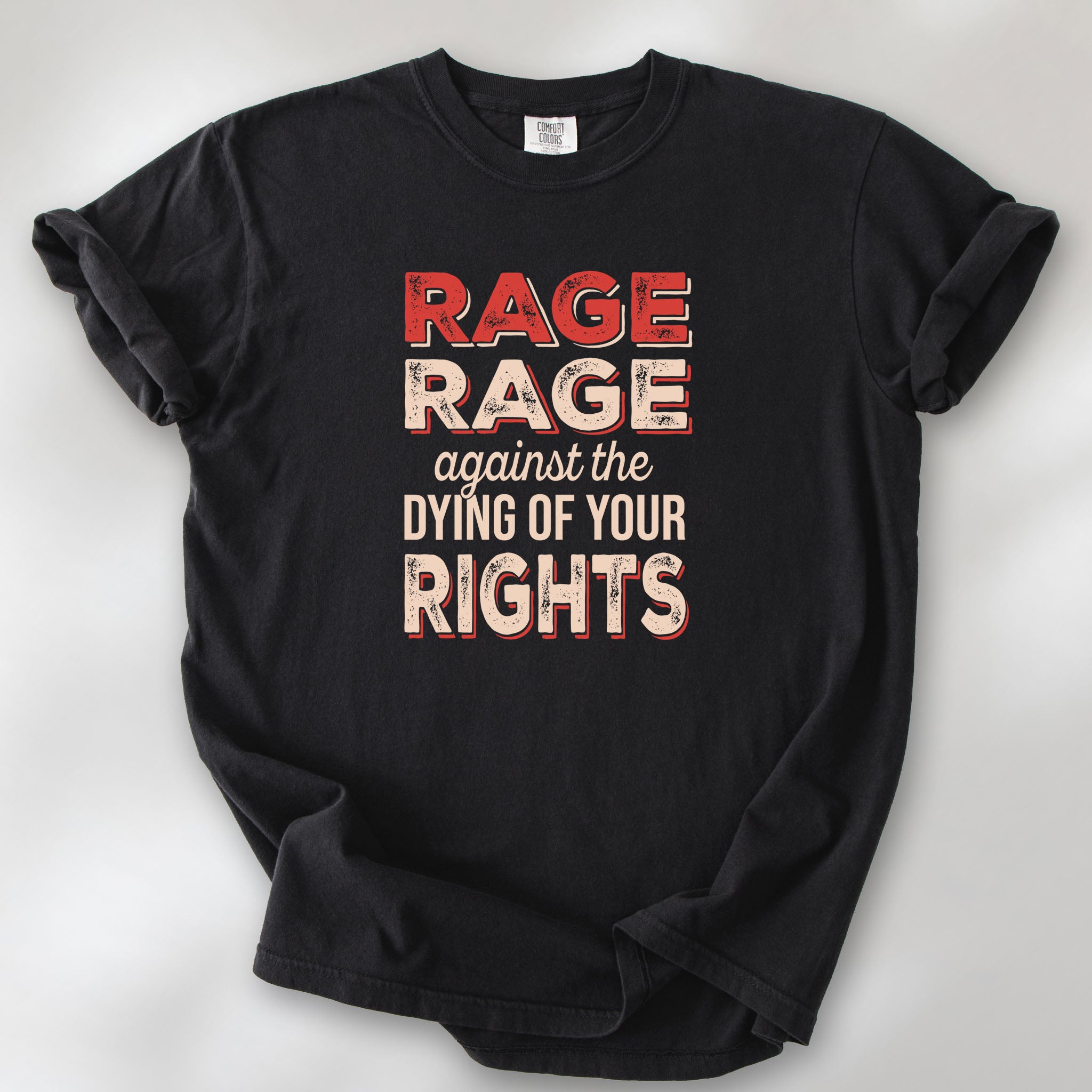 Black unisex Comfort Colors 1717 t-shirt with bold distressed text that reads “RAGE RAGE against the DYING OF YOUR RIGHTS” in red and cream—political protest shirt for liberals and activists.