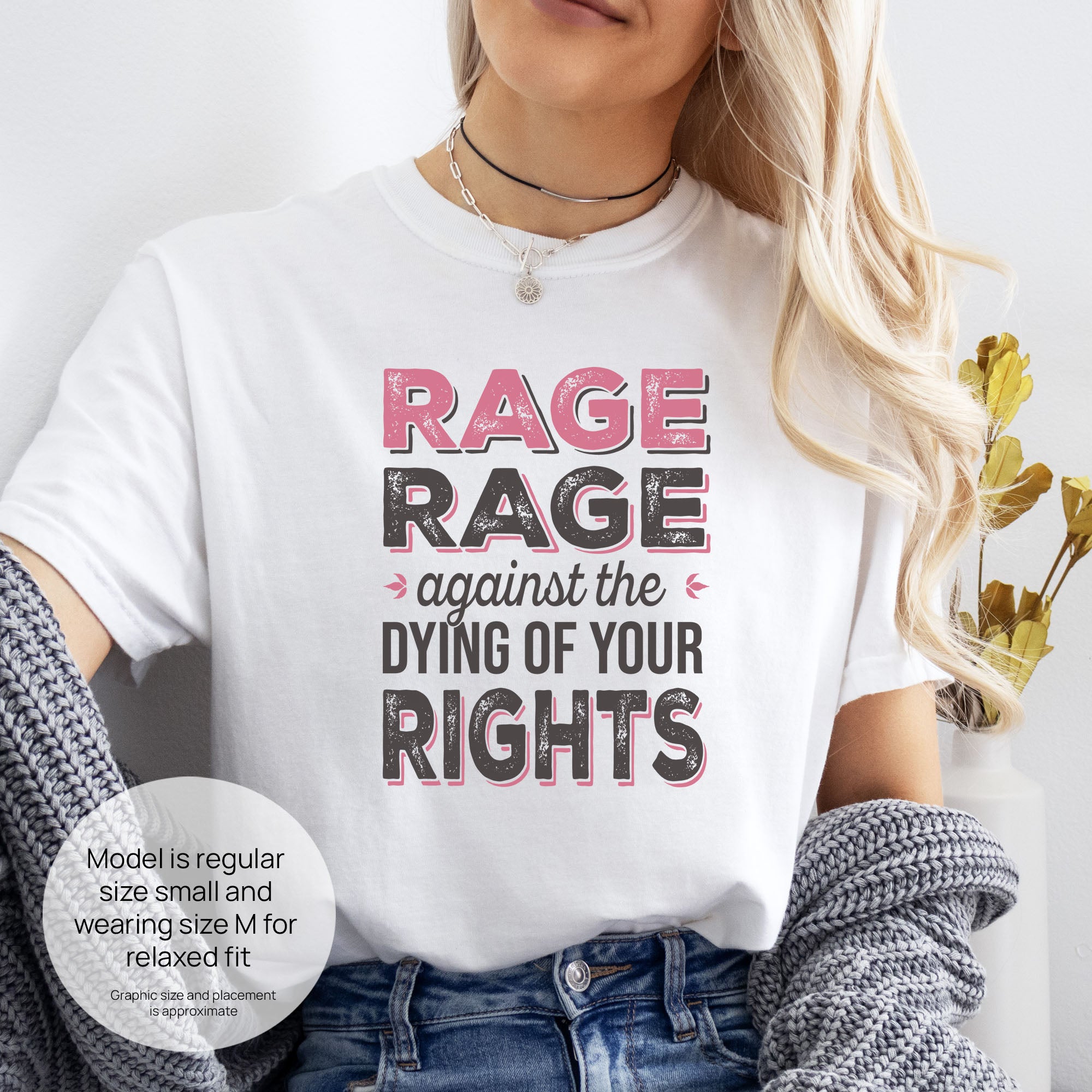 Female model wearing white t-shirt with distressed bold text that reads "rage rage against the dying of your rights". Includes size and fit information for the model who is regular size small, and wearing a size M shirt for a relaxed fit.
