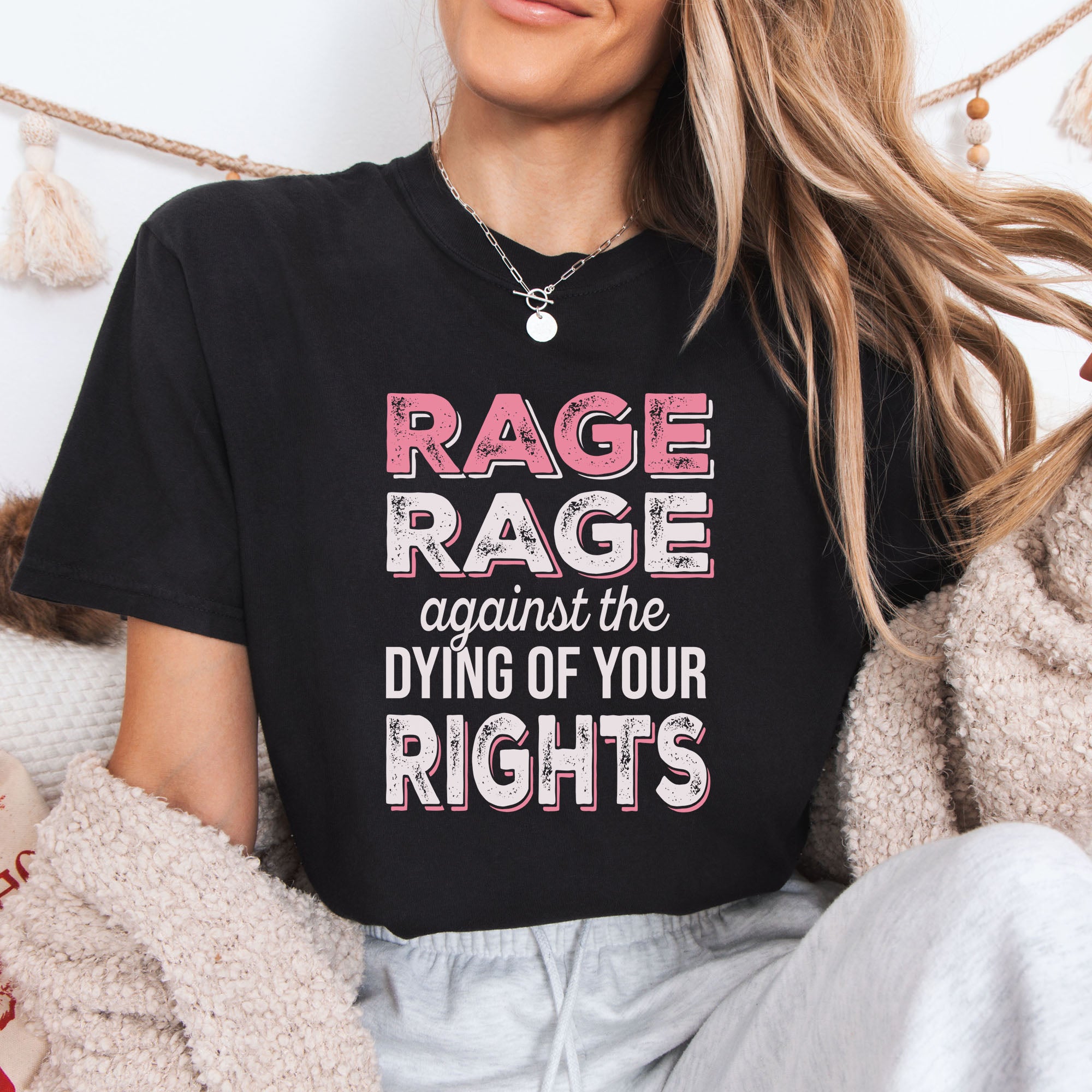 Female model wearing black protest t-shirt with bold pink and white text reading “rage rage against the dying of your rights” – feminist anti-trump activist shirt.