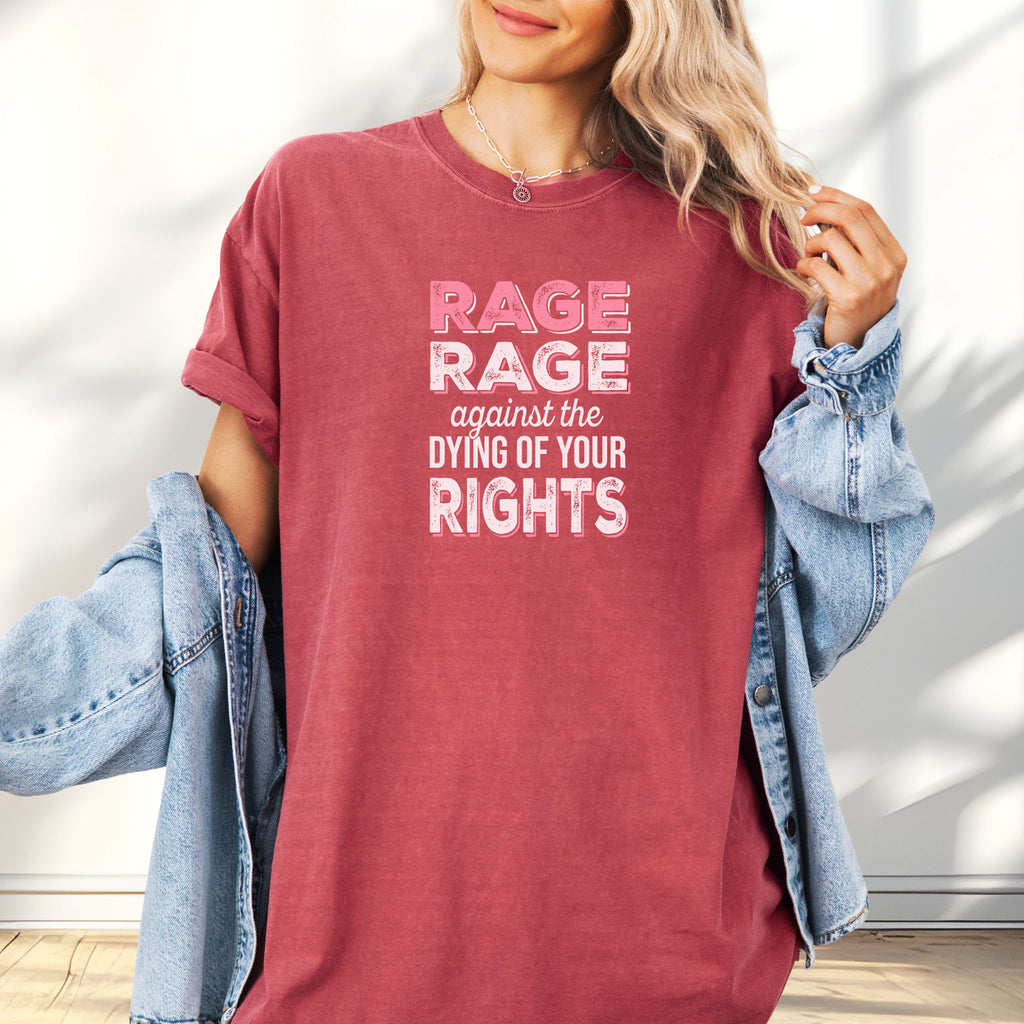 Female model wearing oversized crimson protest t-shirt with bold pink and white text reading “rage rage against the dying of your rights” – feminist anti-trump activist shirt.