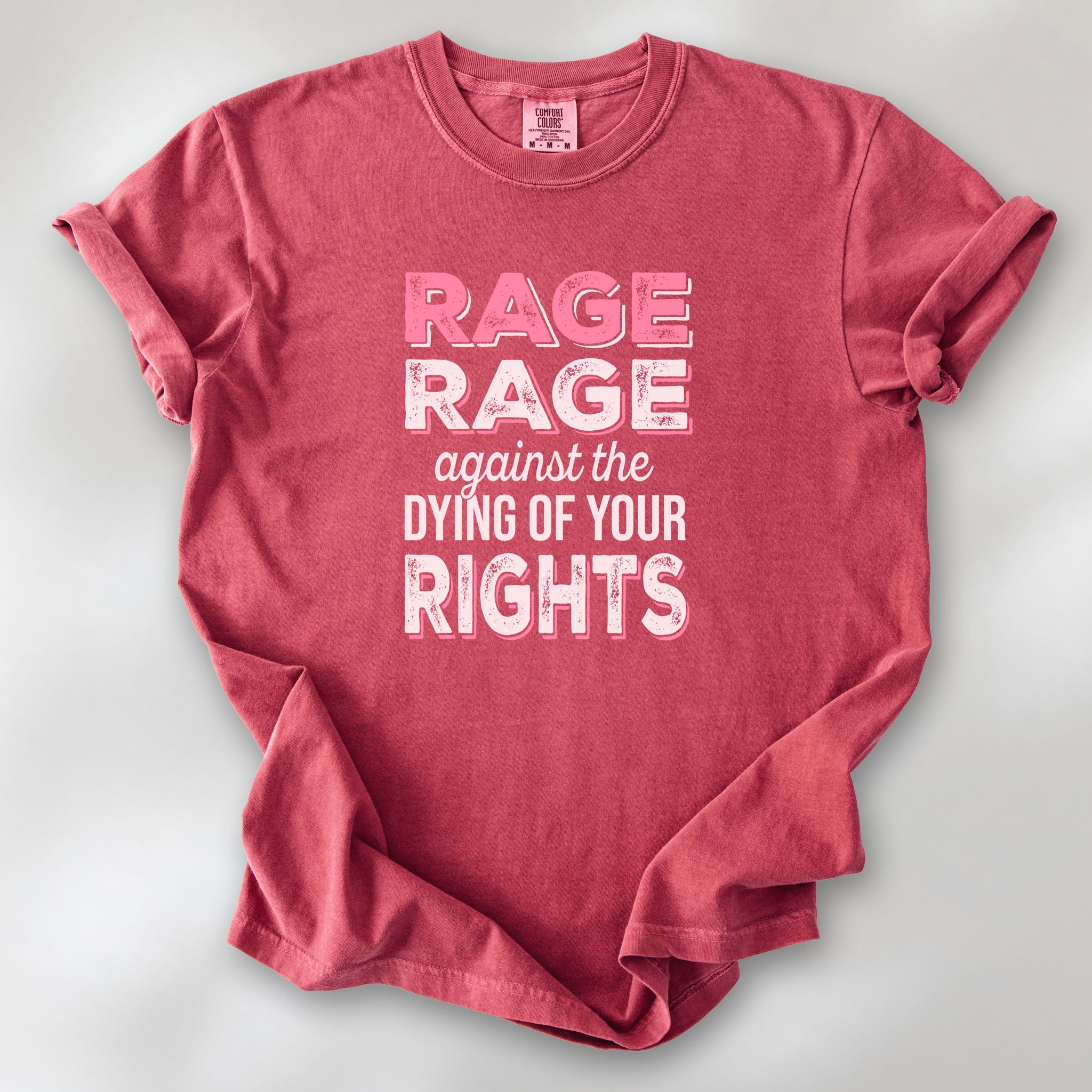 Crimson protest t-shirt with bold pink and white text reading “rage rage against the dying of your rights” – feminist anti-trump activist shirt.