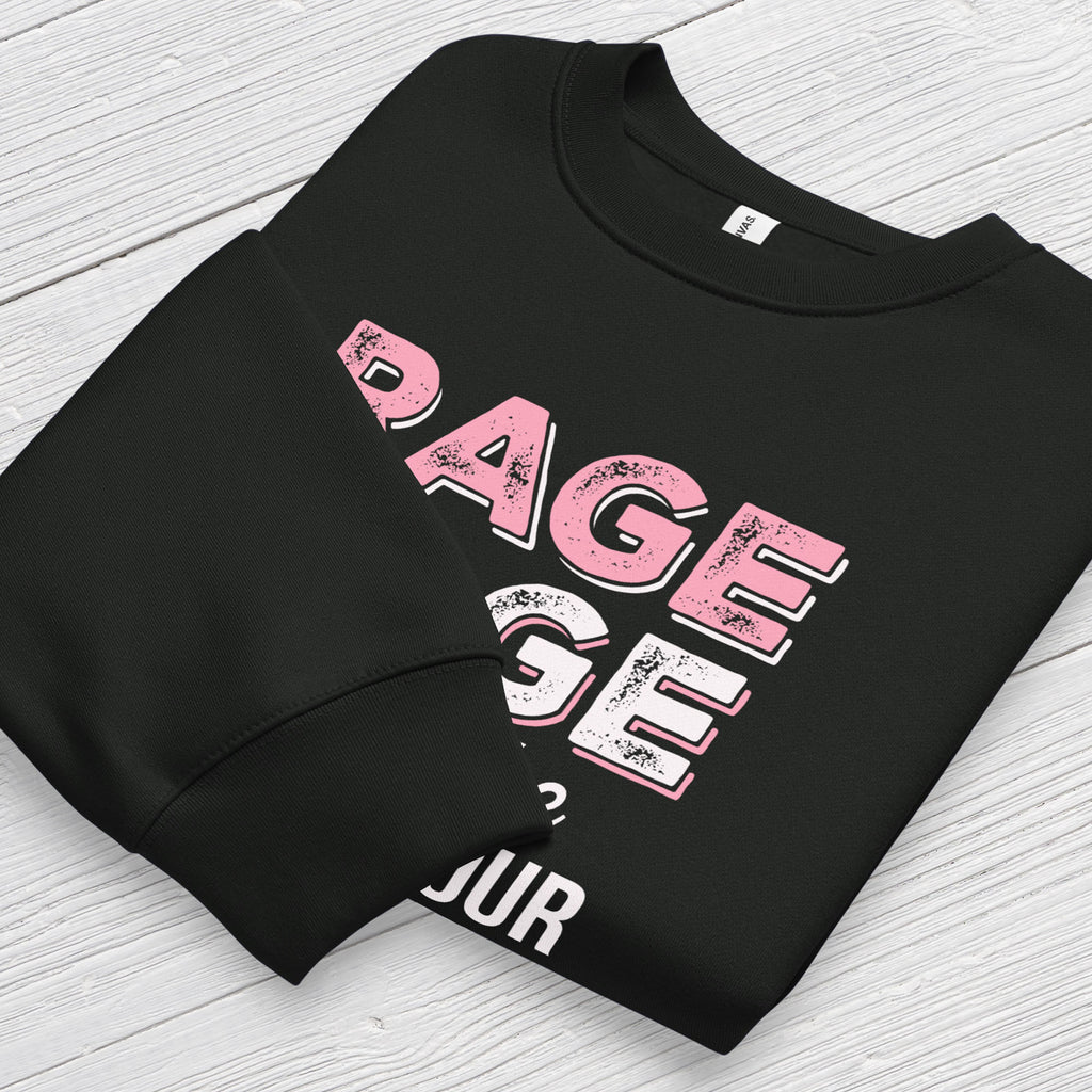 Black protest sweatshirt with bold pink and white text reading “rage rage against the dying of your rights” – feminist anti-trump activist shirt. Folded with cuff detail showing.
