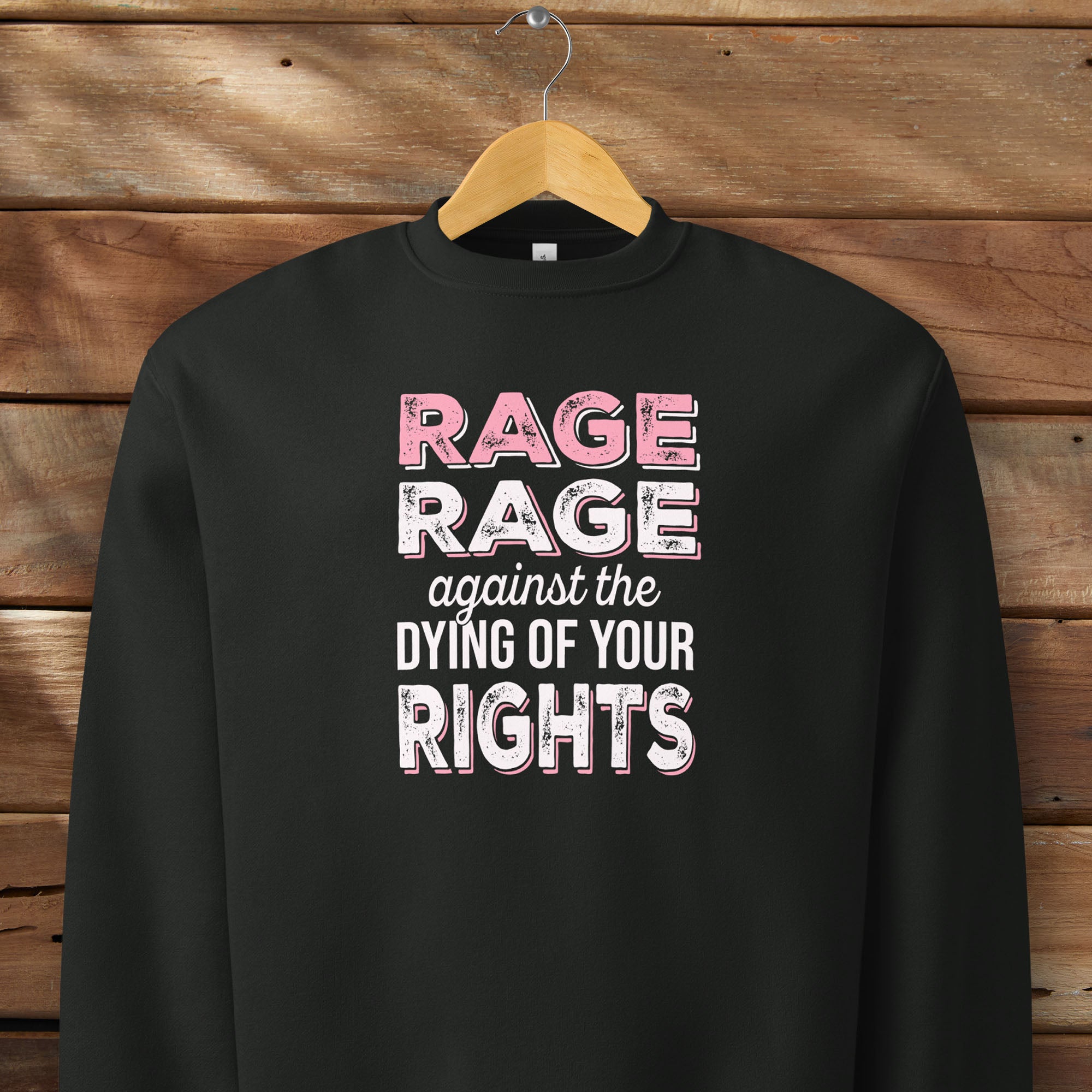 Black protest sweatshirt with bold pink and white text reading “rage rage against the dying of your rights” – feminist anti-trump activist shirt.