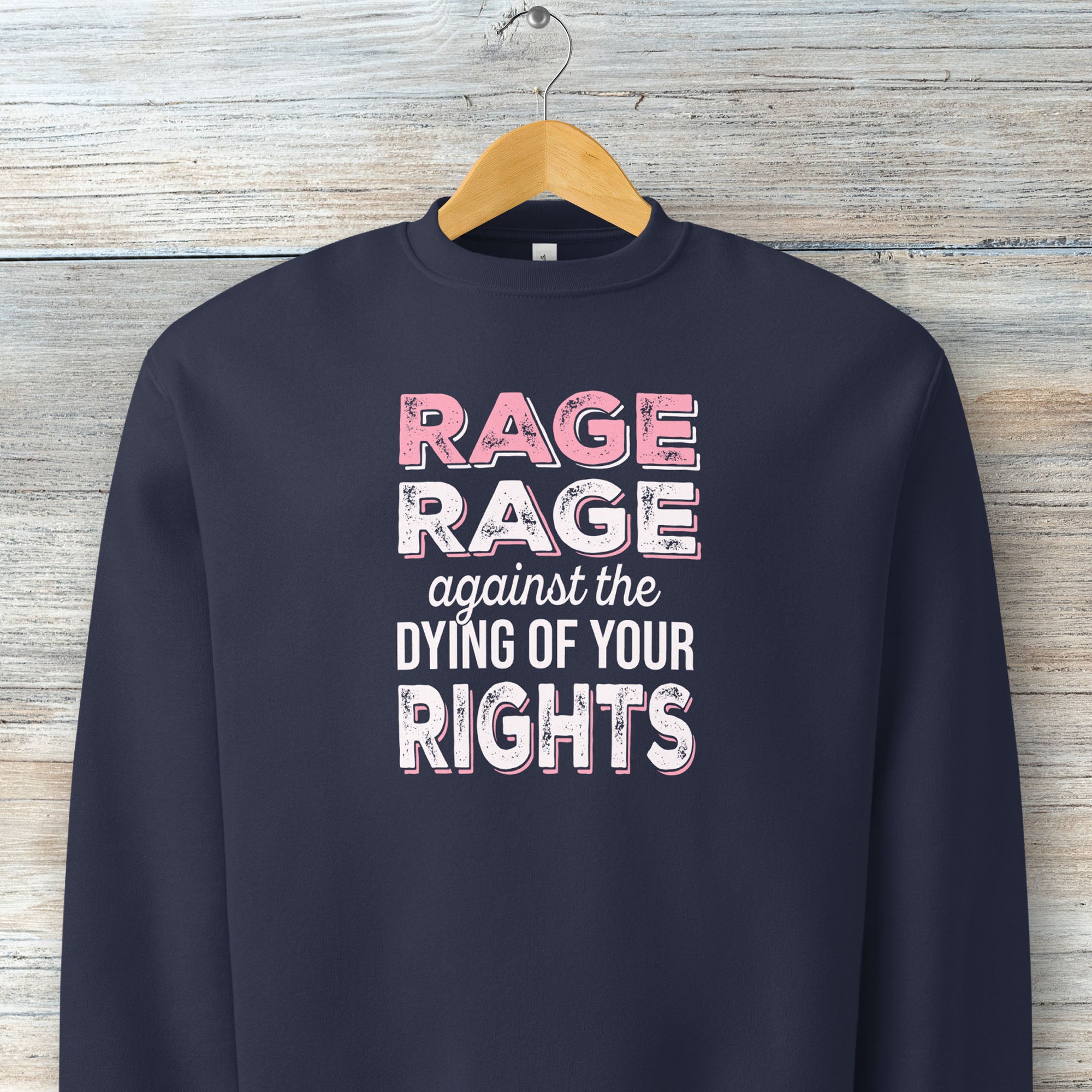 Navy protest sweatshirt with bold pink and white text reading “rage rage against the dying of your rights” – feminist anti-trump activist shirt.