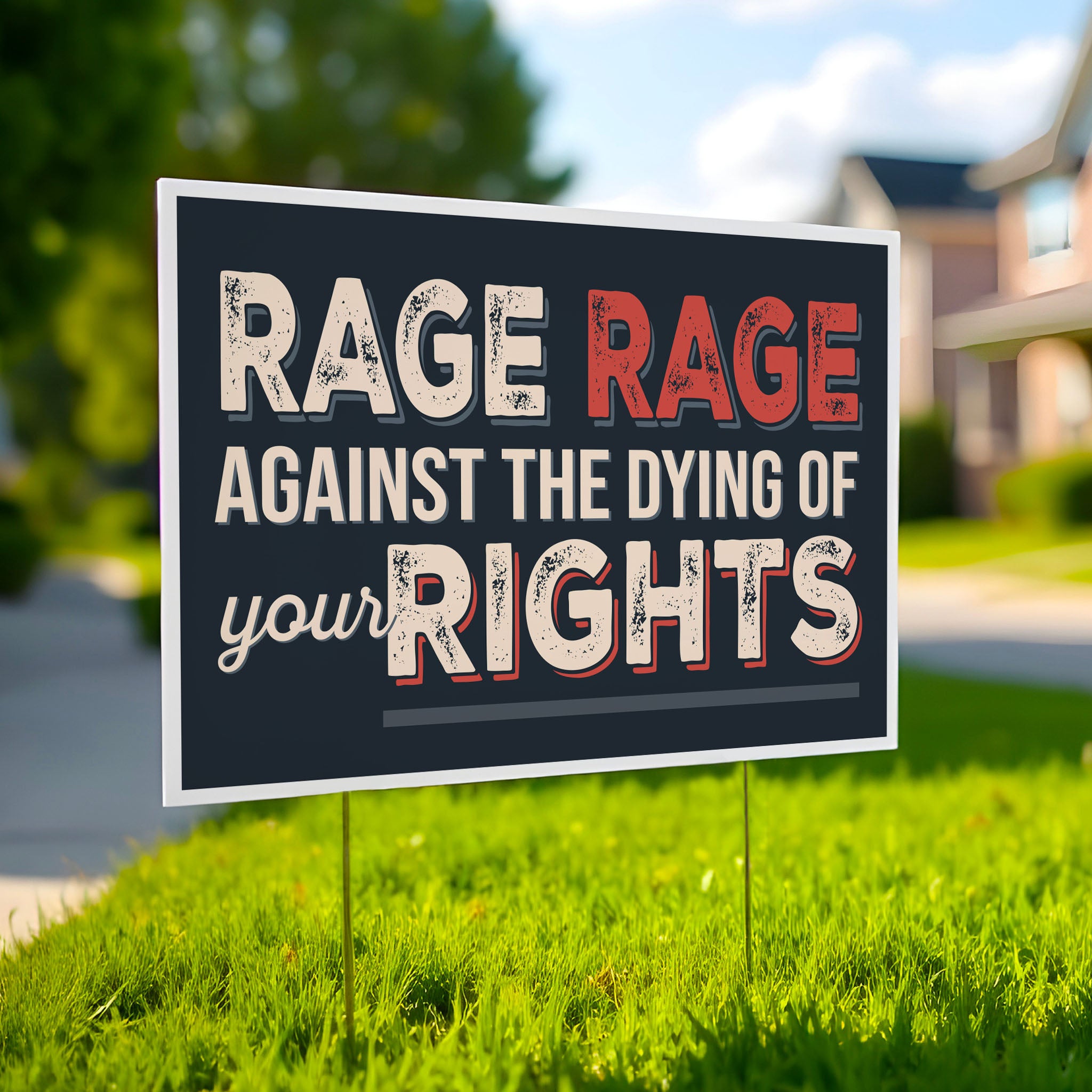 Protest sign with text that reads "Rage rage against the dying of your rights," a political twist to the line from a Dylan Thomas poem, planted in a green lawn.