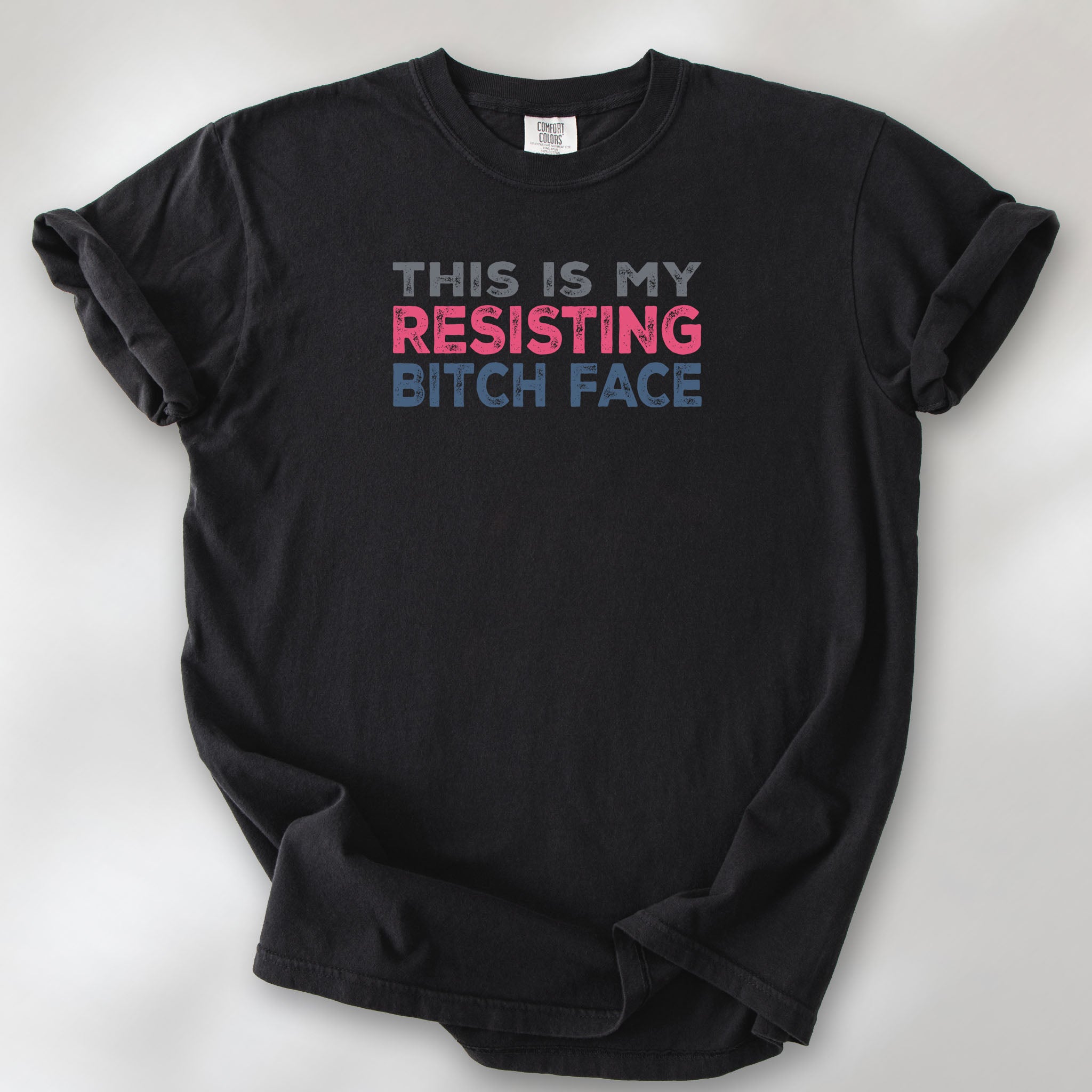 Black t-shirt with bold text that reads "This Is My Resisting Bitch Face" in gray, pink, and blue distressed font – a strong feminist and political protest shirt ideal for activism and making a bold statement.