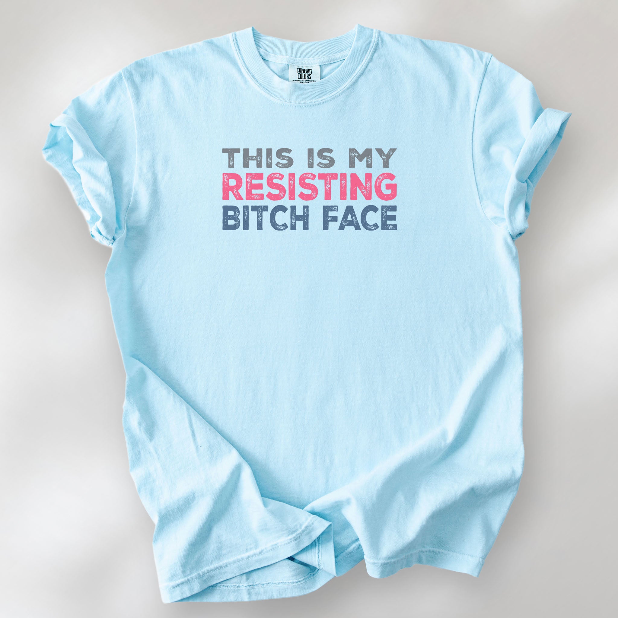 Chambray t-shirt with bold text that reads "This Is My Resisting Bitch Face" in gray, pink, and blue distressed font – a strong feminist and political protest shirt ideal for activism and making a bold statement.