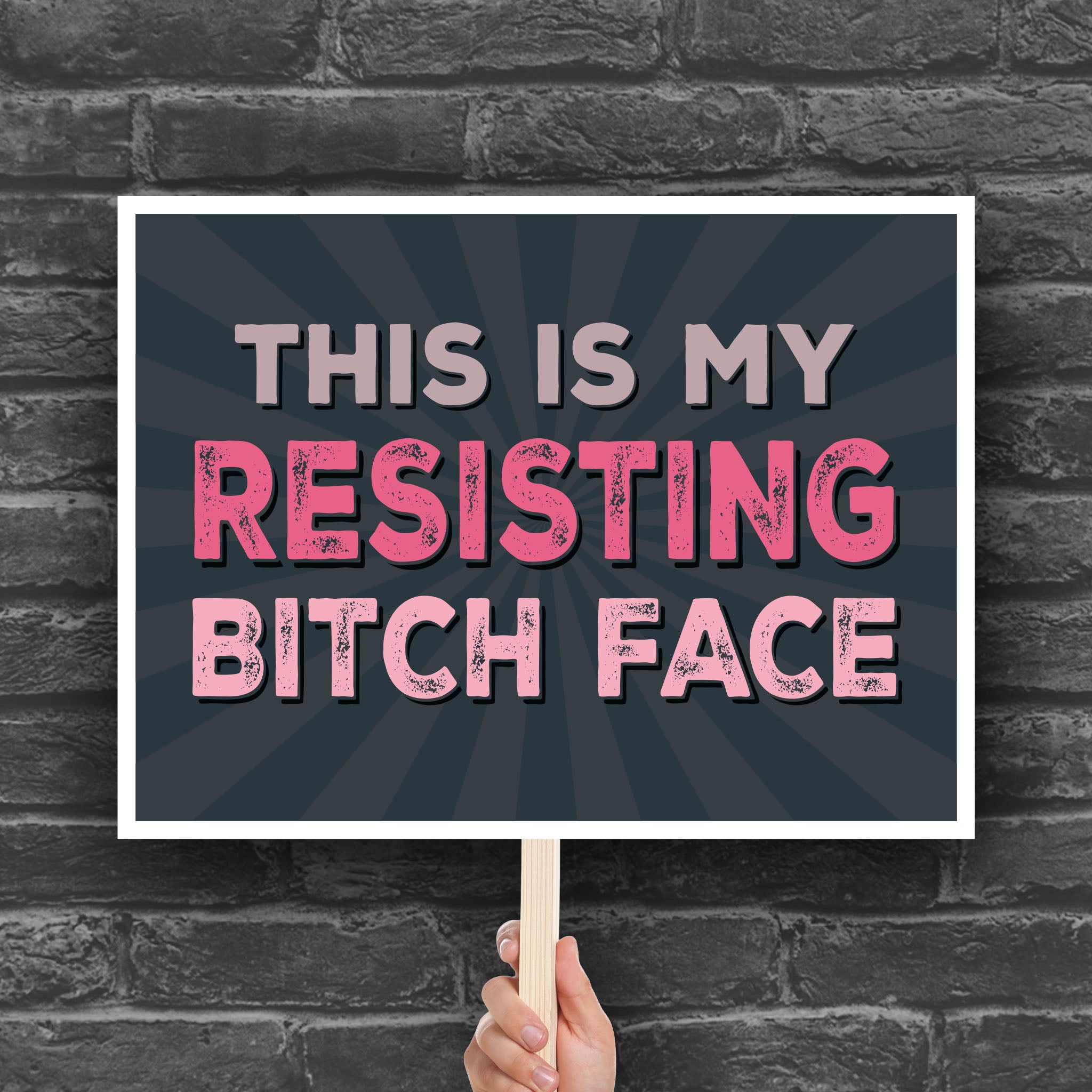 Downloadable, printable anti-trump protest sign with a black background and pink distressed text that reads "This is my resisting bitch face" in all uppercase letters.