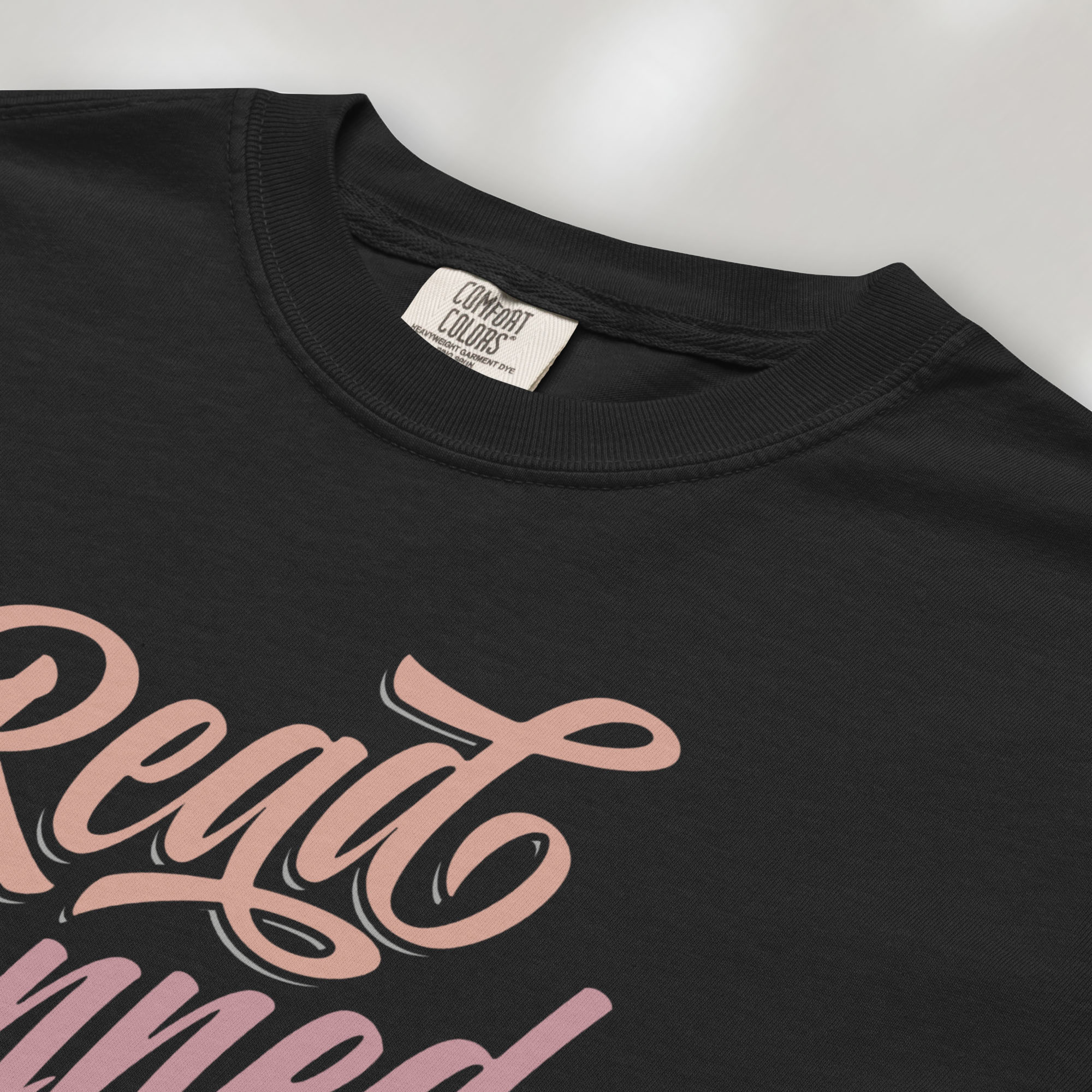 Closeup detail of black black t-shirt with stylized text reading “Read Banned Books” in bold script lettering.