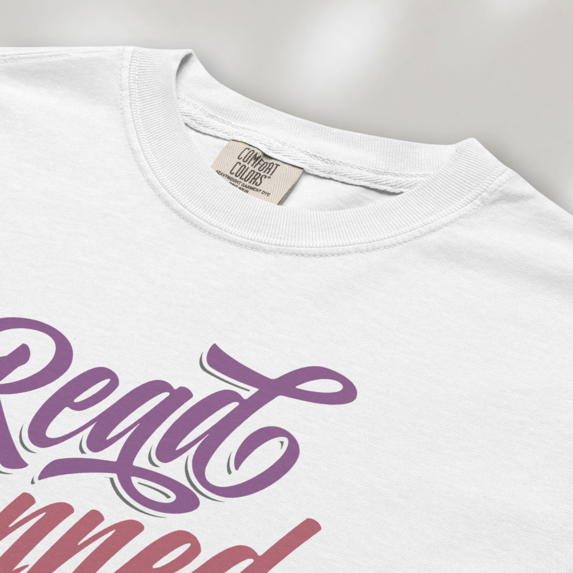 Closeup detail of white t-shirt with stylized text reading “Read Banned Books” in bold script lettering.